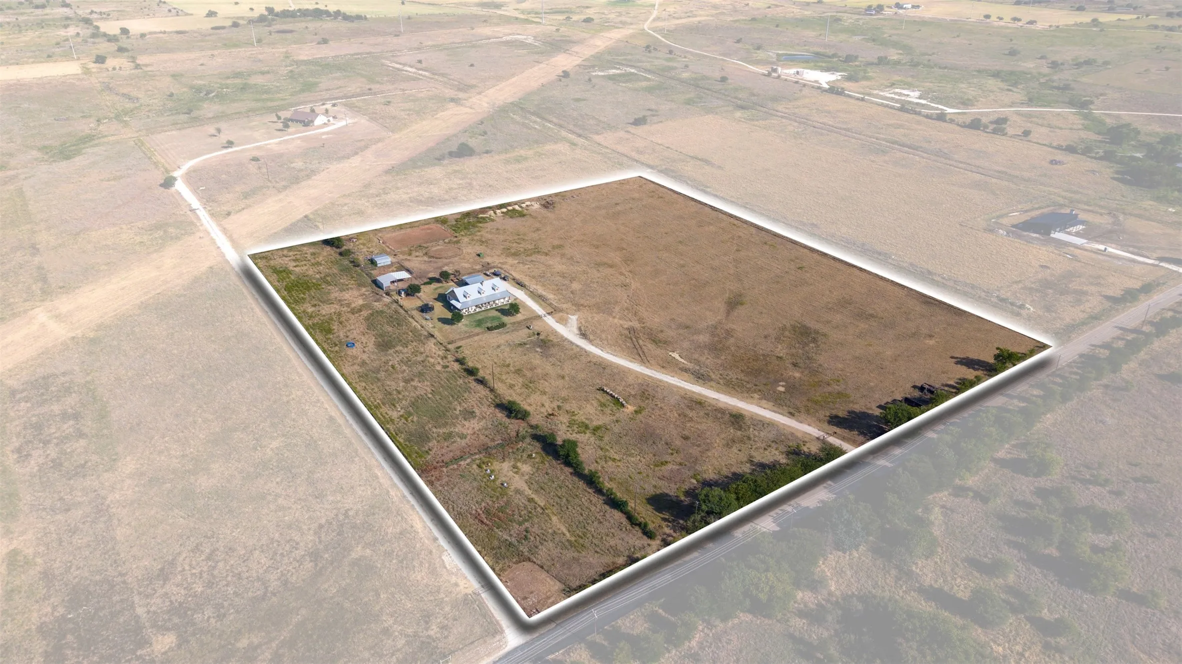 Expansive rural acreage with a main residence, outbuildings, and a private driveway