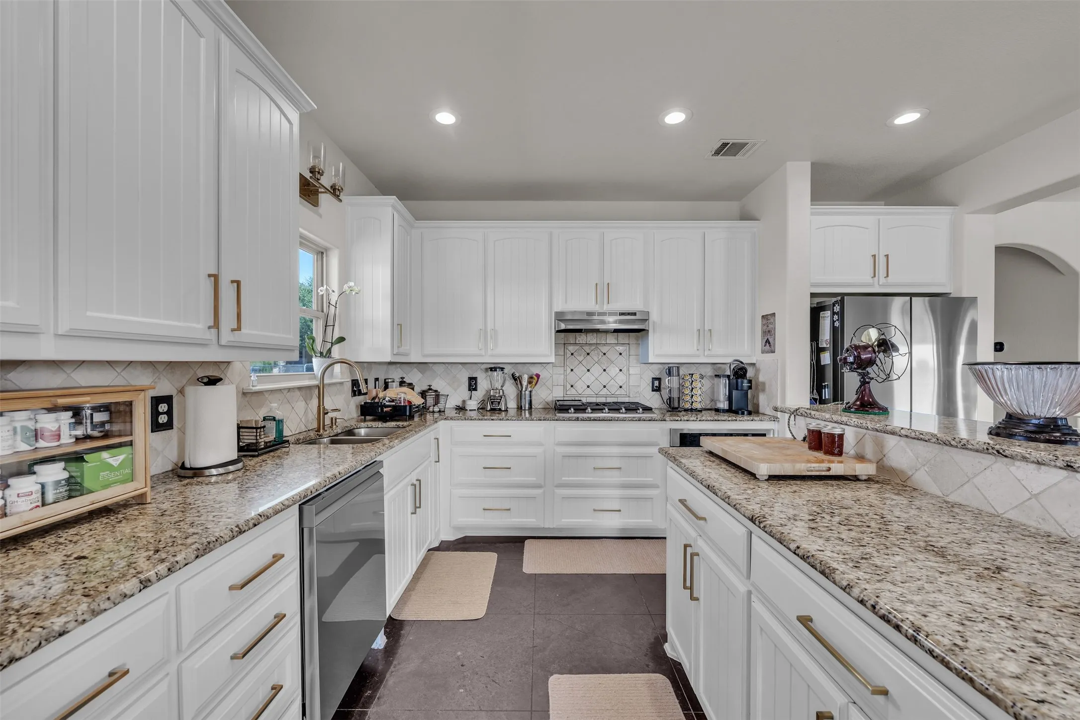 Kitchen featuring white cabinetry, stone countertops, stainless steel appliances, a tile backsplash, and recessed lighting