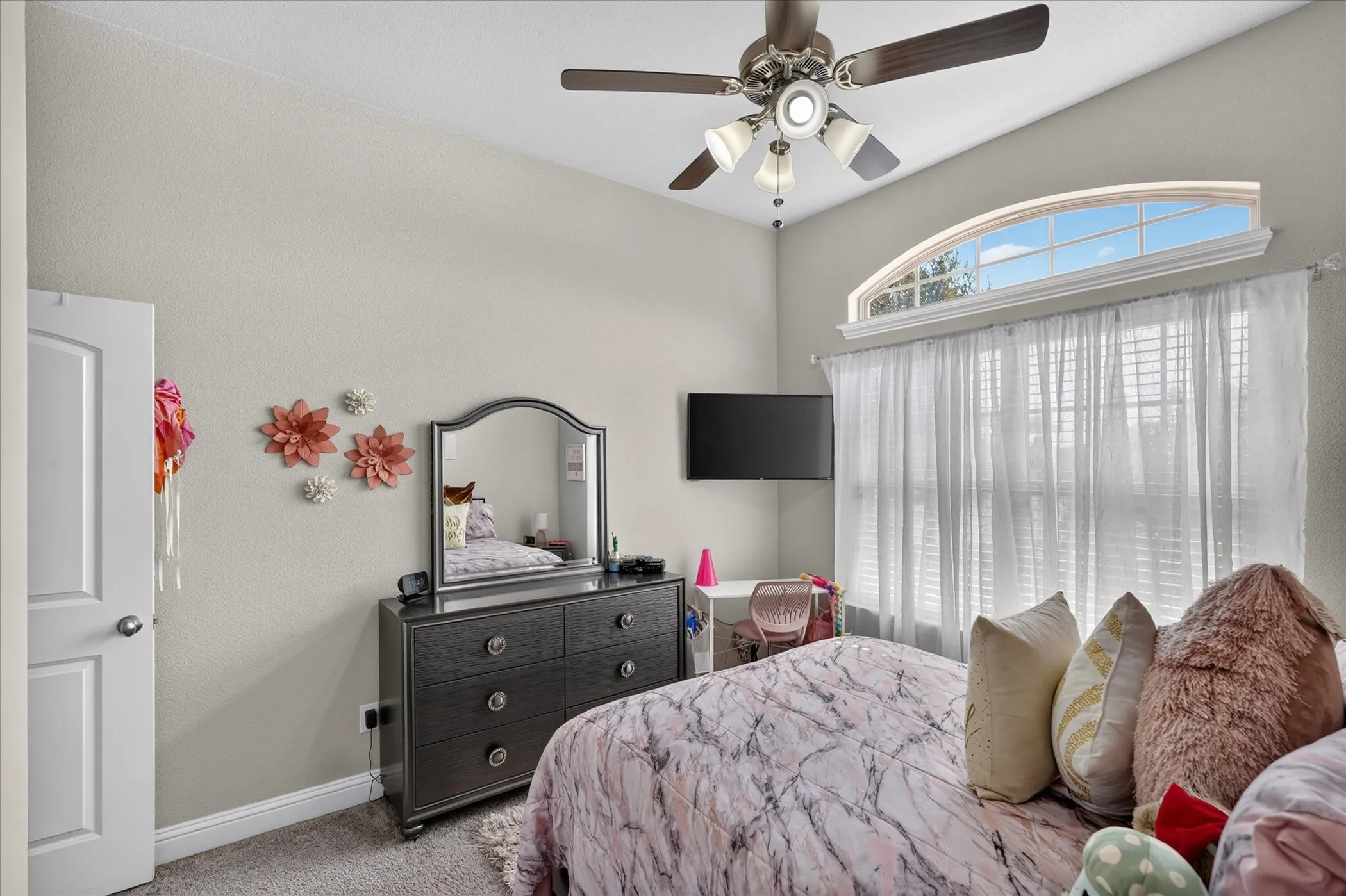 Arched transom window, vaulted ceiling, and ceiling fan with integrated lighting