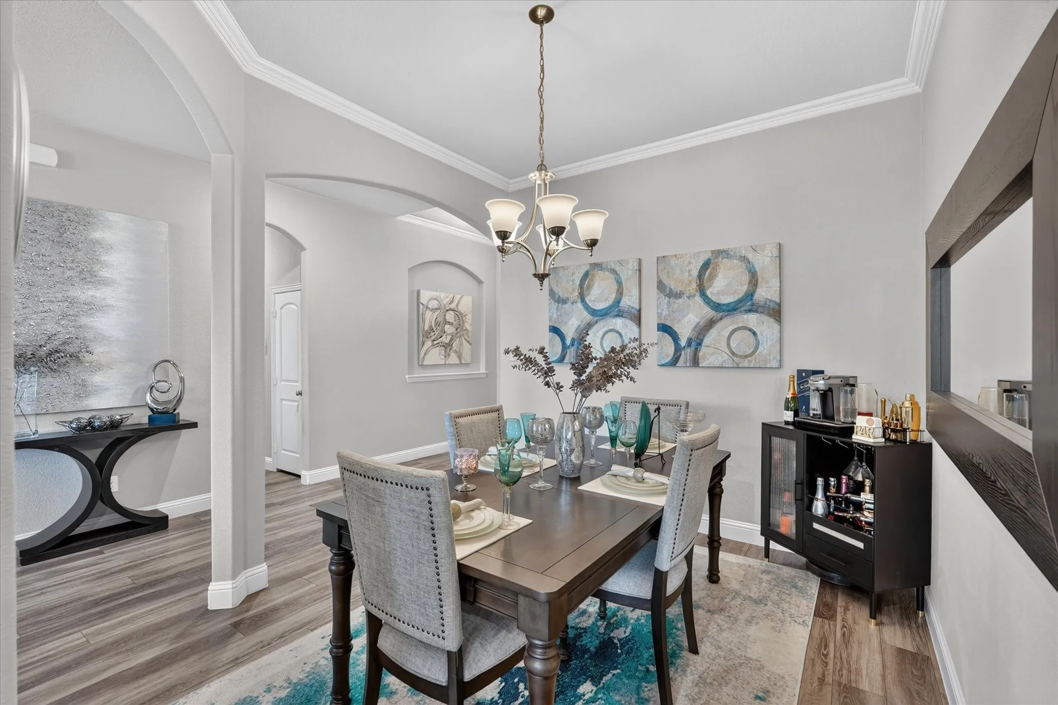 Wood-finish flooring throughout, crown molding, arched doorways, and a built-in beverage cabinet