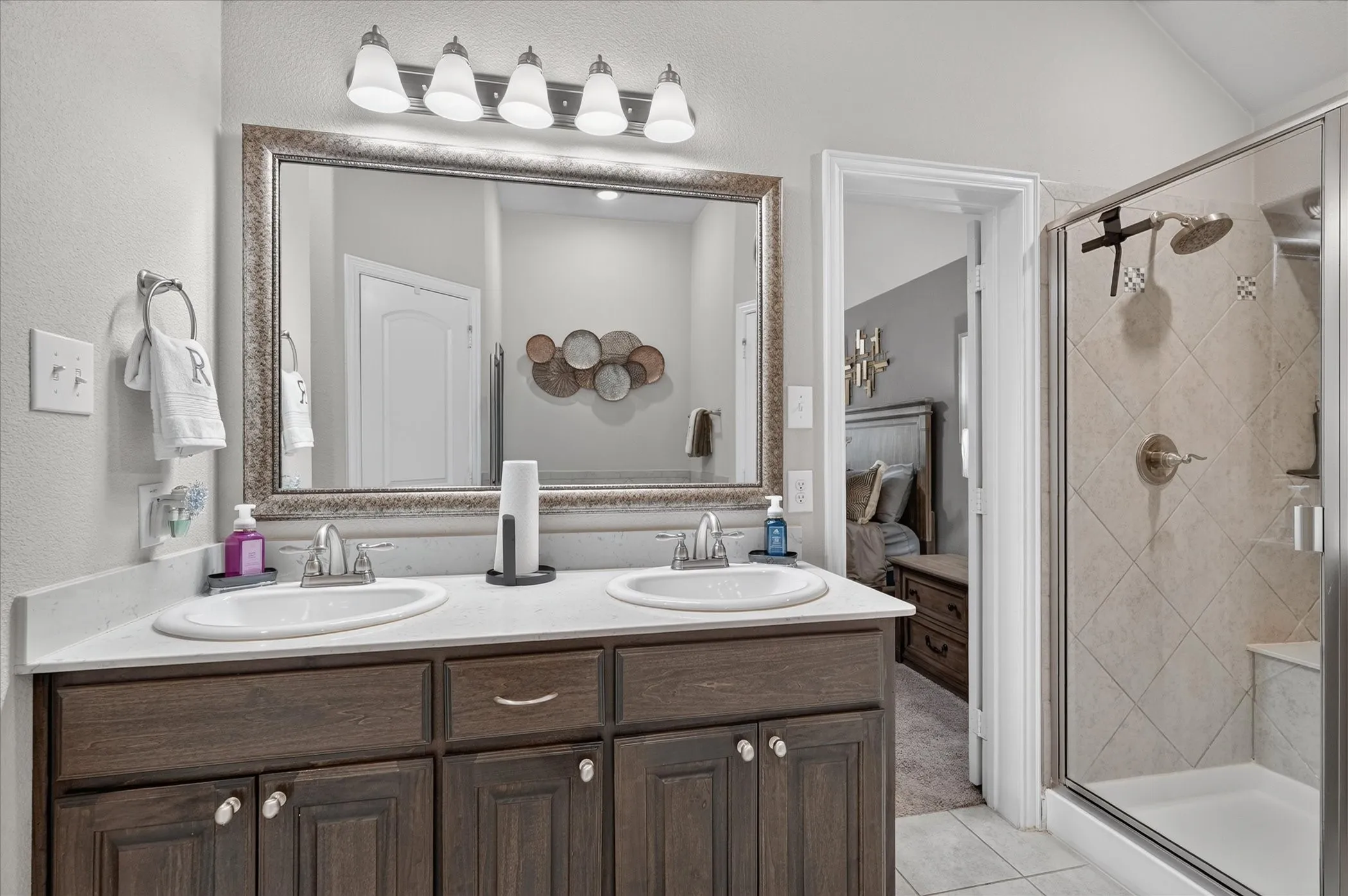 Double vanity with white oval sinks, white countertops, and dark wood-finish cabinetry