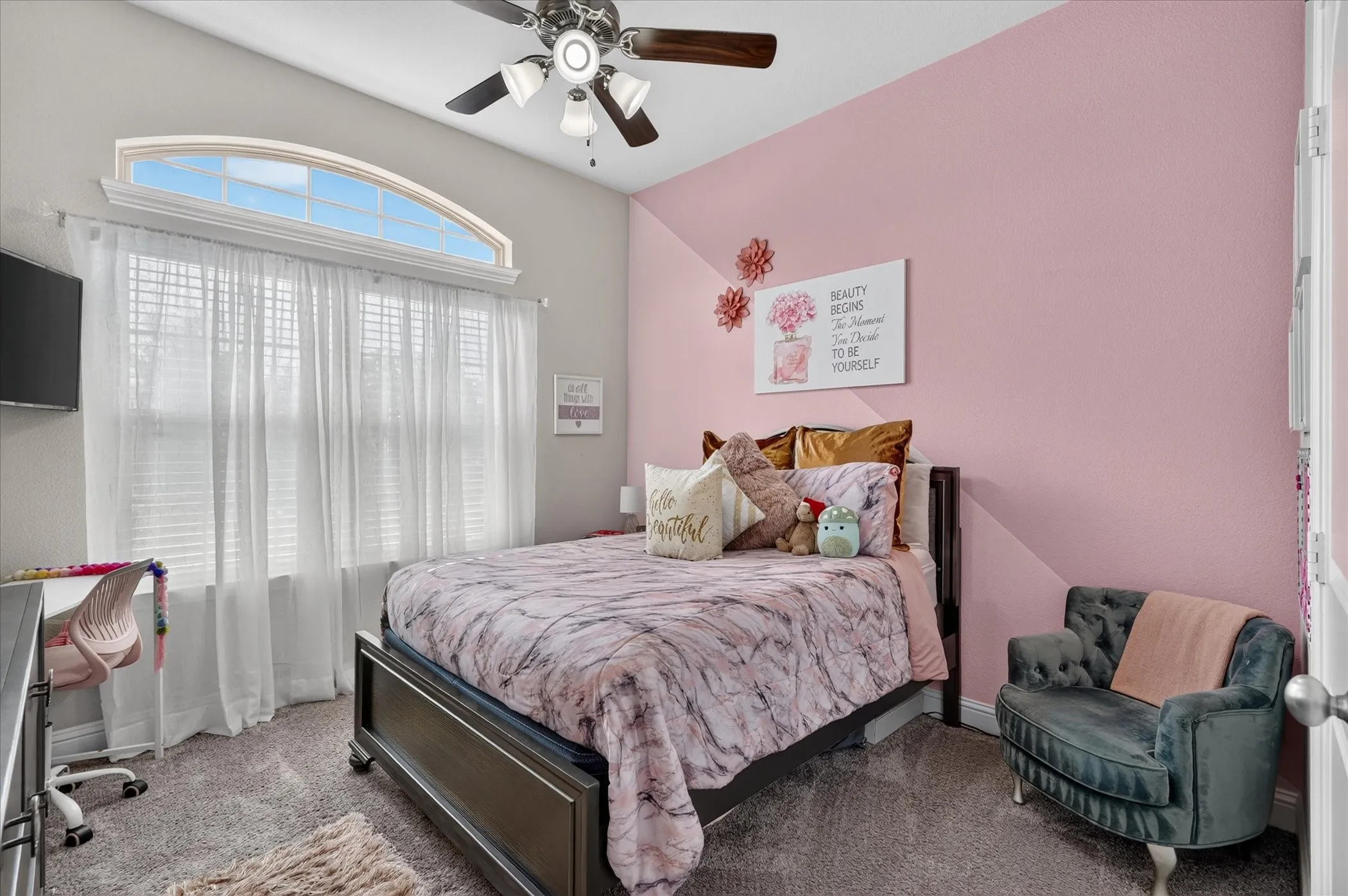Arched transom window above a large window, ceiling fan with integrated lighting, and carpeted flooring