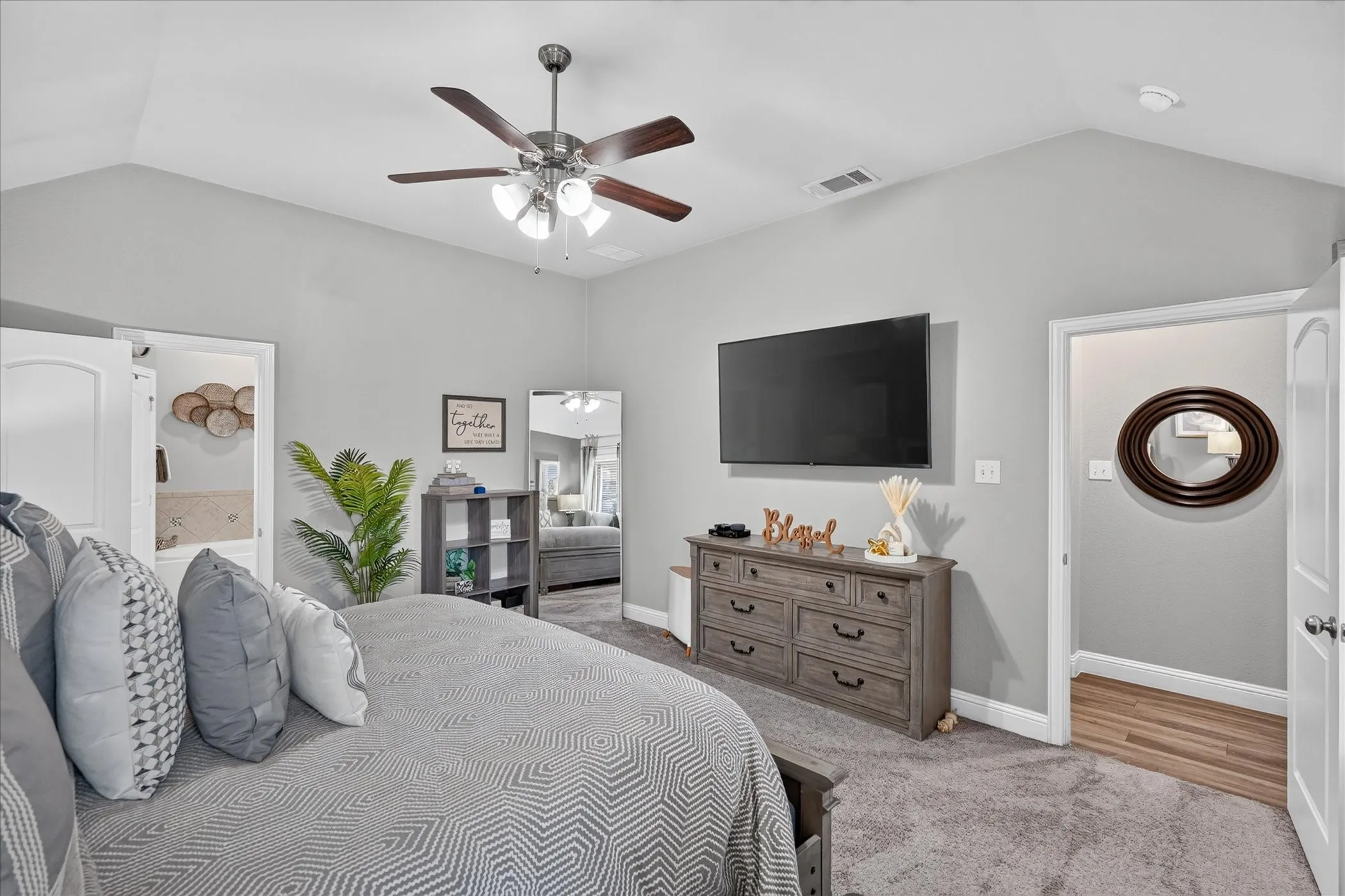 Vaulted ceiling featuring a ceiling fan with light fixture, wall-mounted television, and carpet flooring