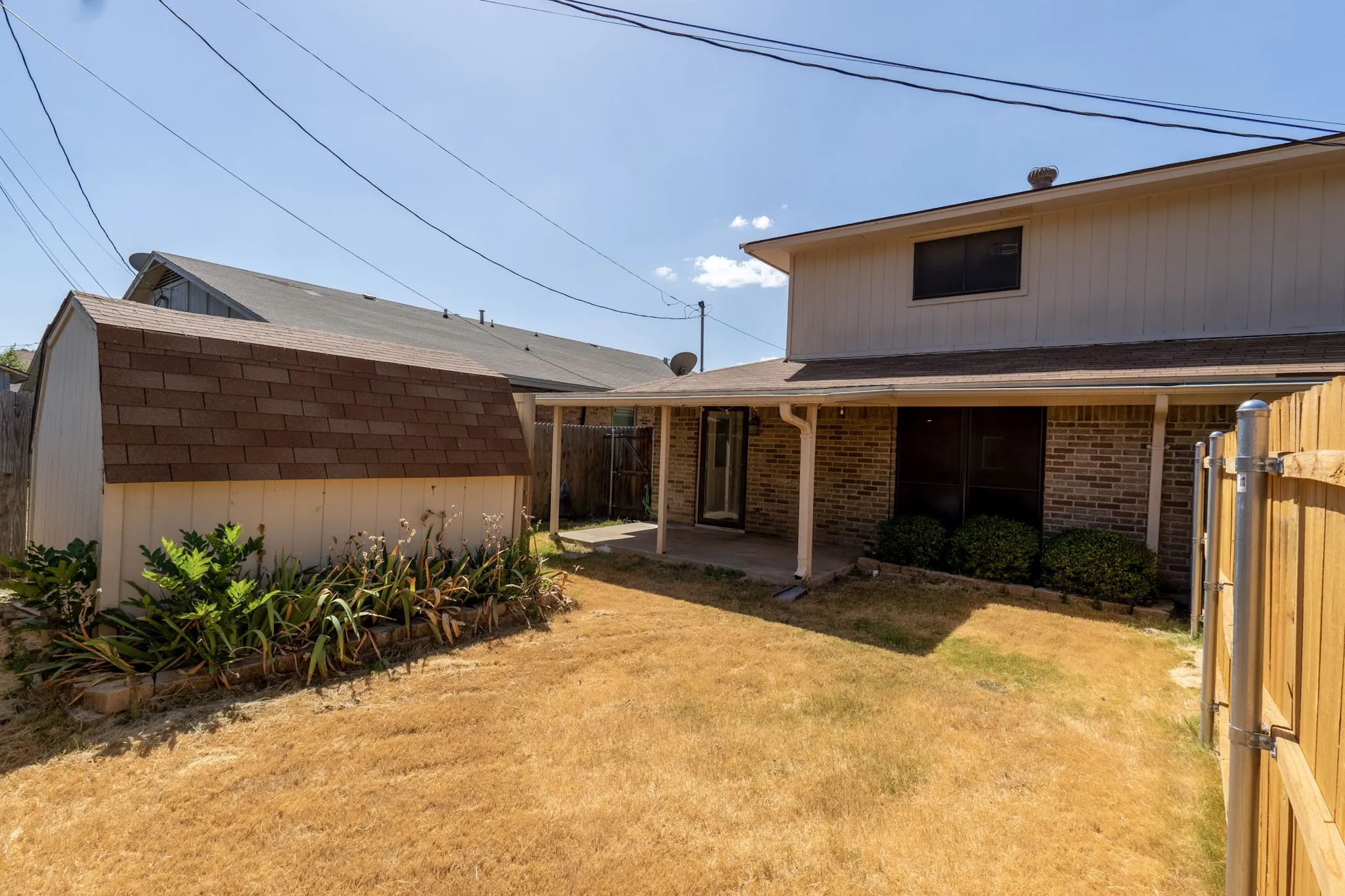 Backyard featuring a shed with shingle roofing, a covered patio, brick exterior, and a wood privacy fence