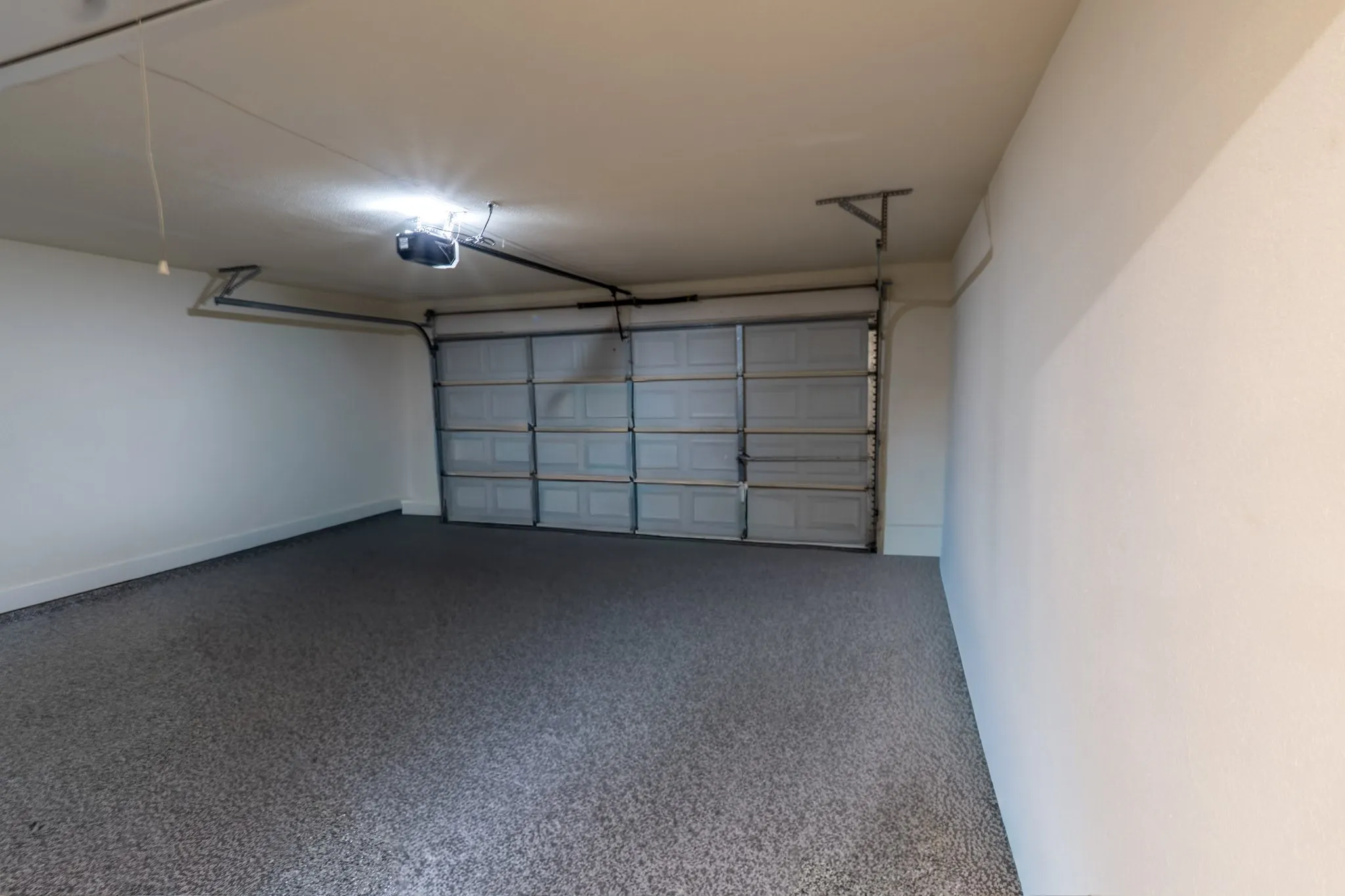 Attached garage with a textured floor finish, overhead garage door, and bright overhead lighting