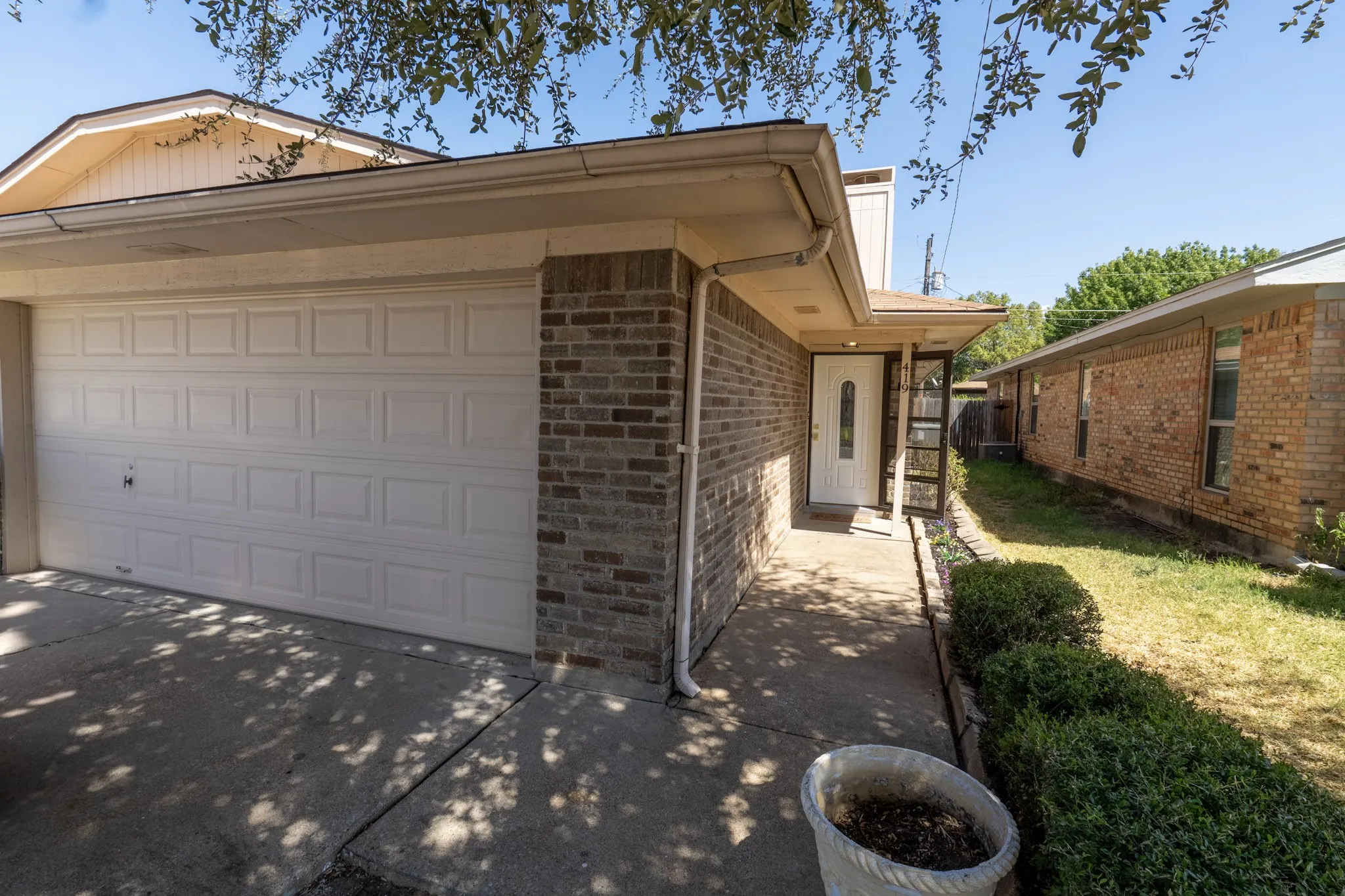 Brick exterior with a white paneled garage door, covered entryway, and a front door with decorative glass inserts