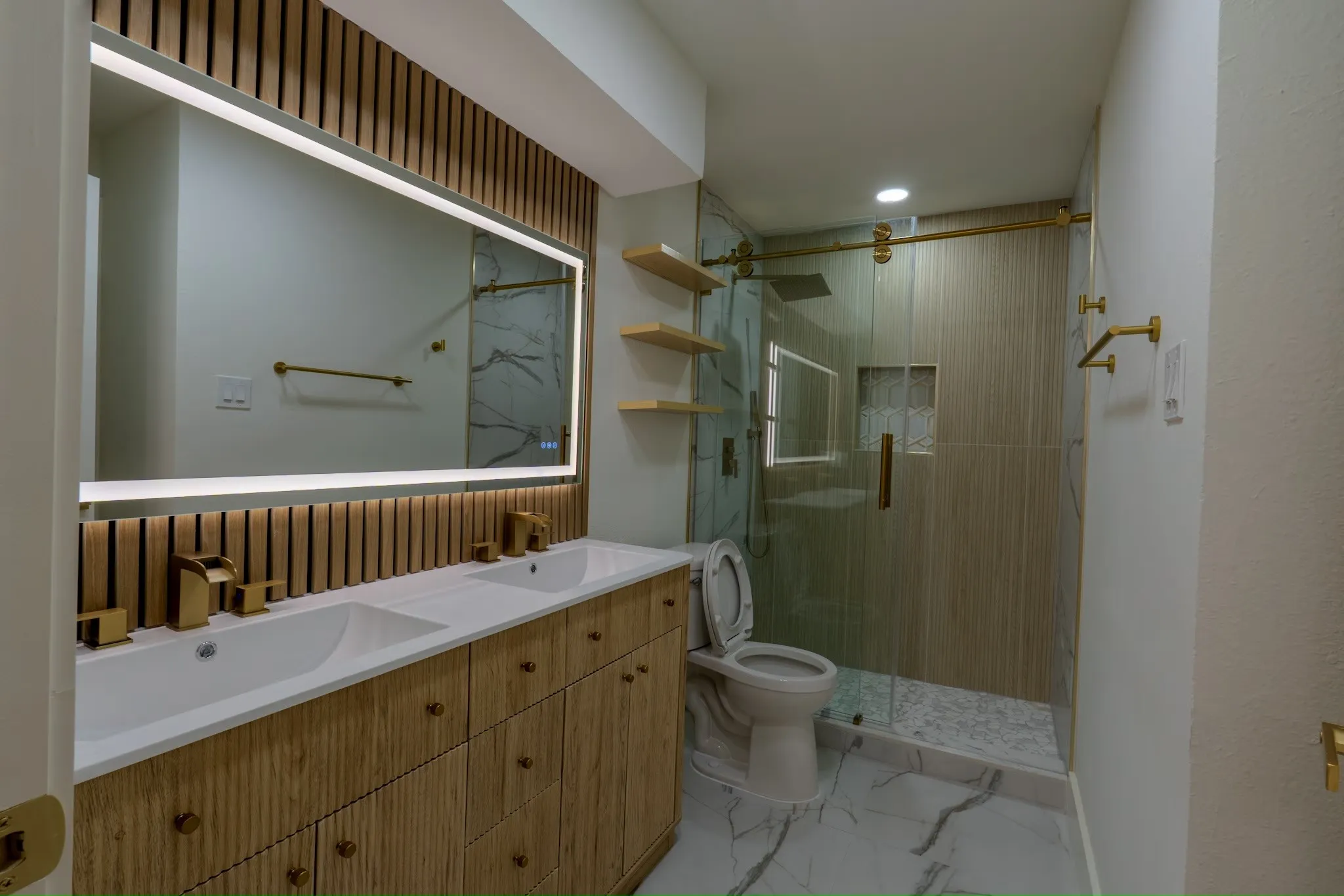 Double vanity with gold-tone fixtures and back-lit mirror