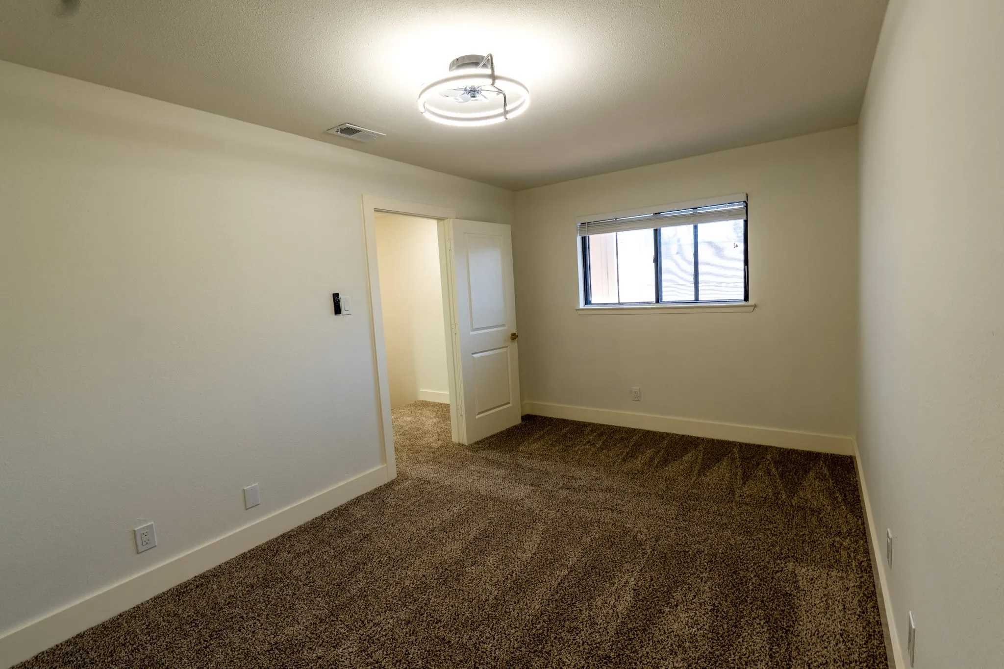 Recessed ceiling light fixture, neutral wall color, built-in window, door with paneling, and wall-to-wall carpeting