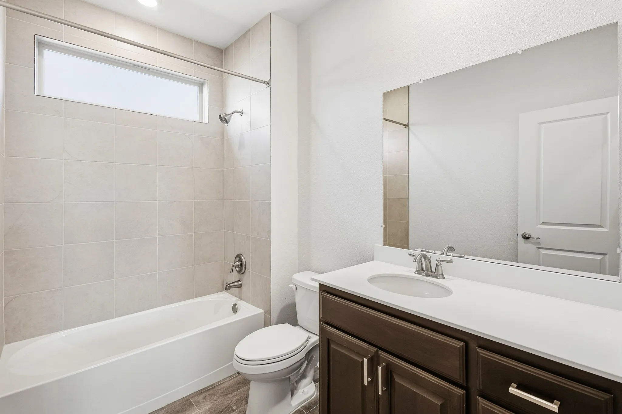 Bathroom featuring a single vanity with dark wood-finish cabinetry, white countertop, and an integrated sink