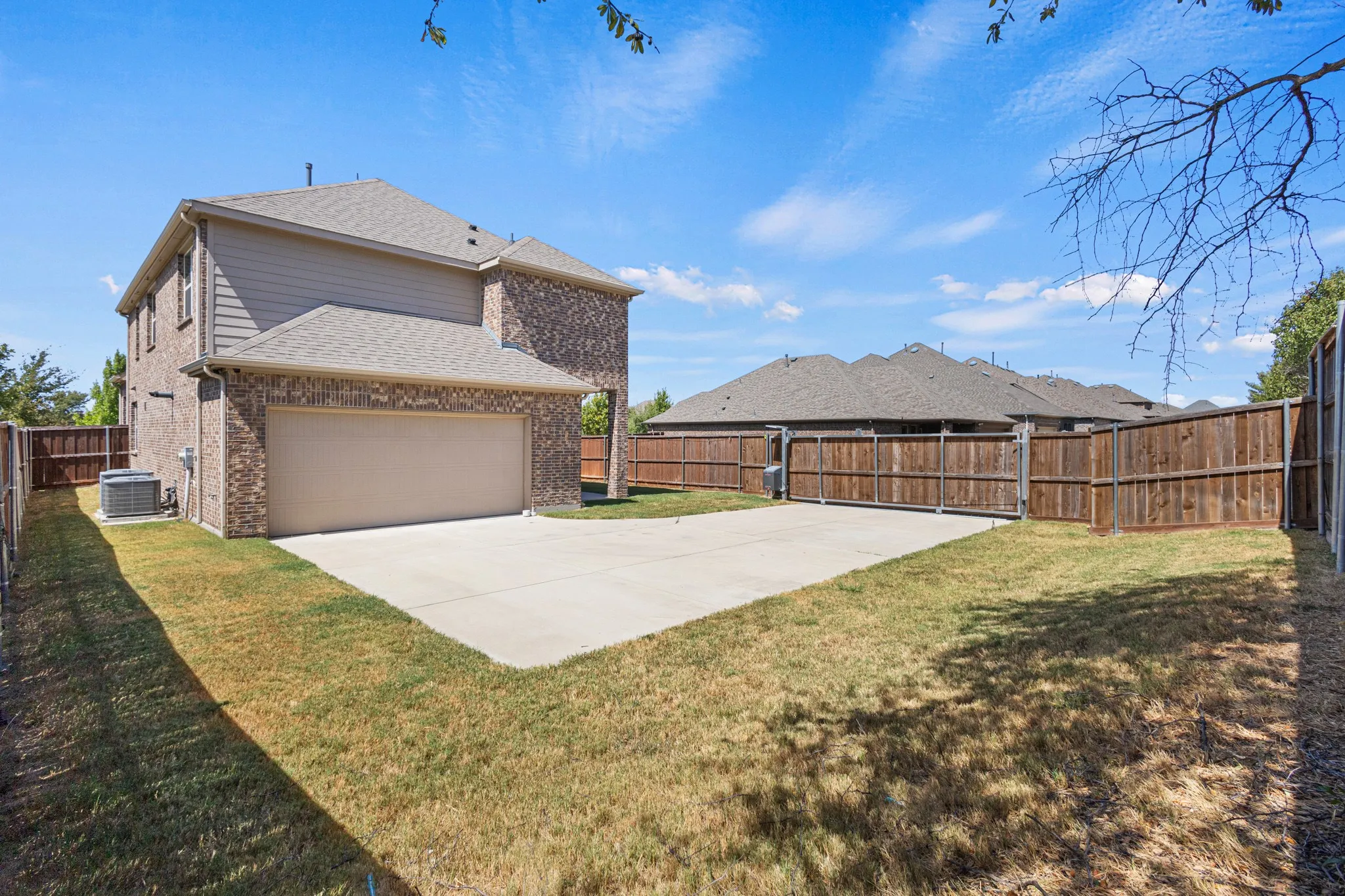 Brick exterior with siding accents, attached garage, concrete driveway, and wood privacy fencing