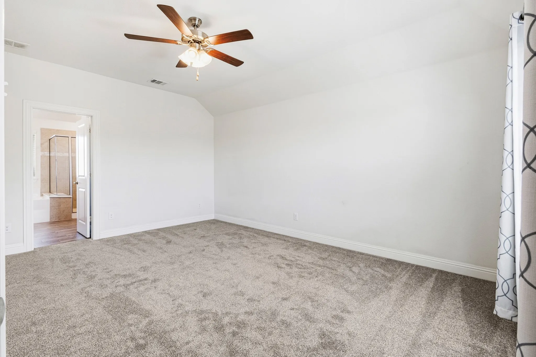 Spacious room with light gray carpeting, a ceiling fan with integrated lighting, and white wall finishes
