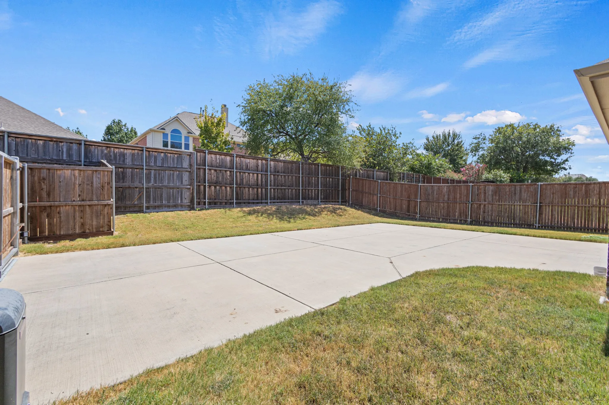 Private backyard featuring a concrete patio, wood fencing, and a grassy area