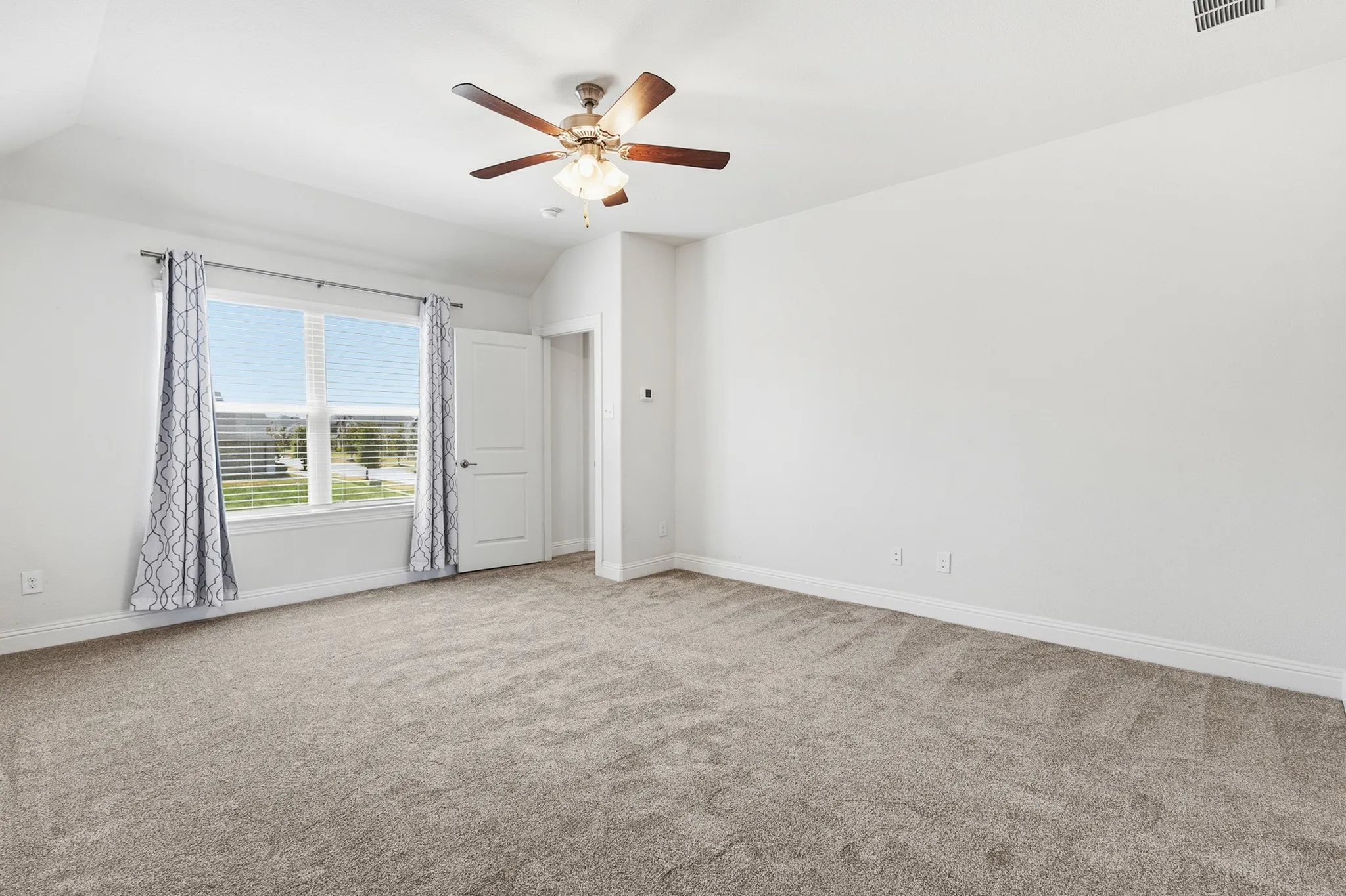 Carpeted room with a ceiling fan, a window with blinds, and a white paneled door