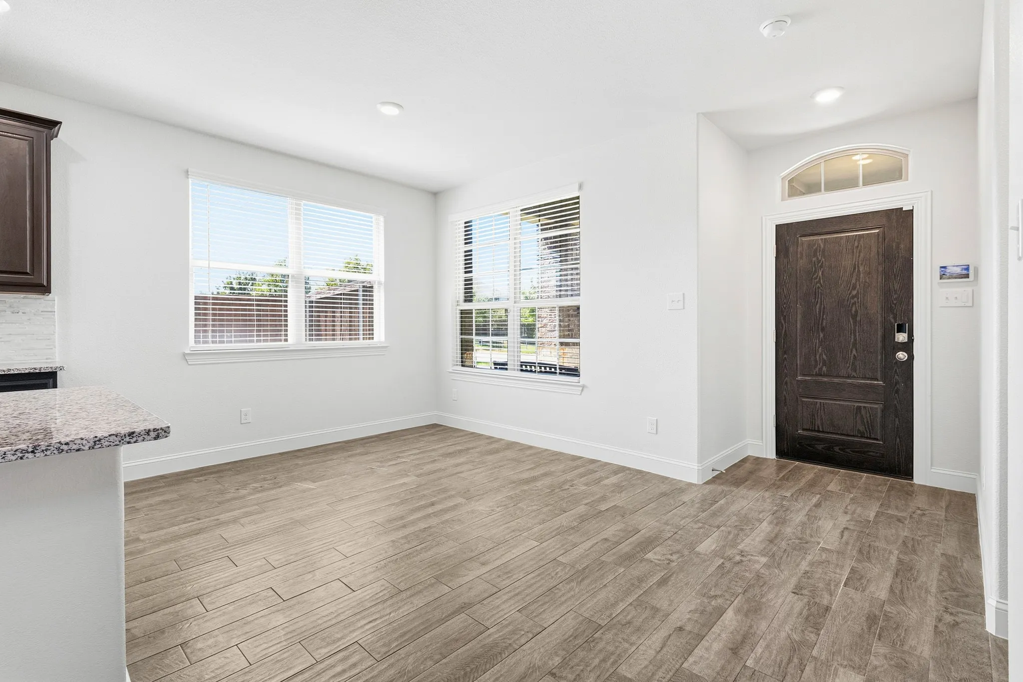 Wood-finish flooring, recessed lighting, and a dark wood entry door with an arched transom window
