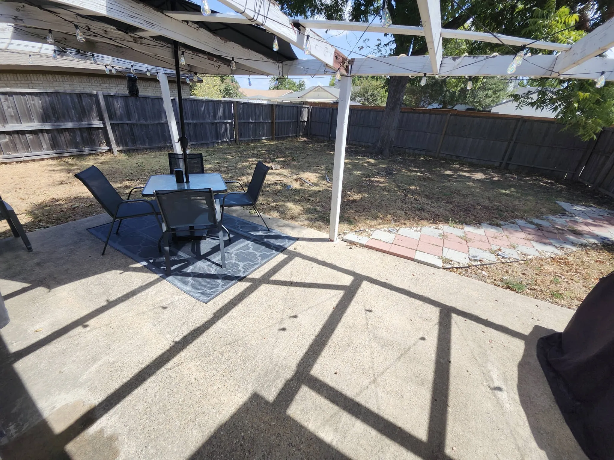 Concrete patio with a wooden pergola structure and string lighting