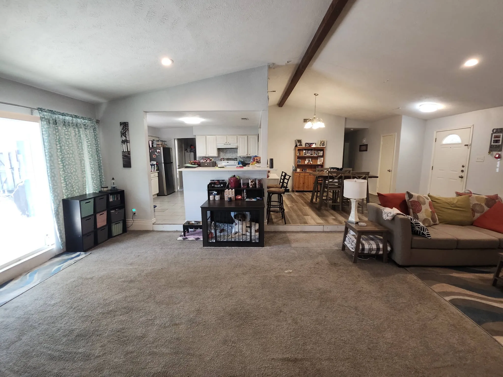 Open-concept living area with vaulted ceilings, recessed lighting, and exposed ceiling beam