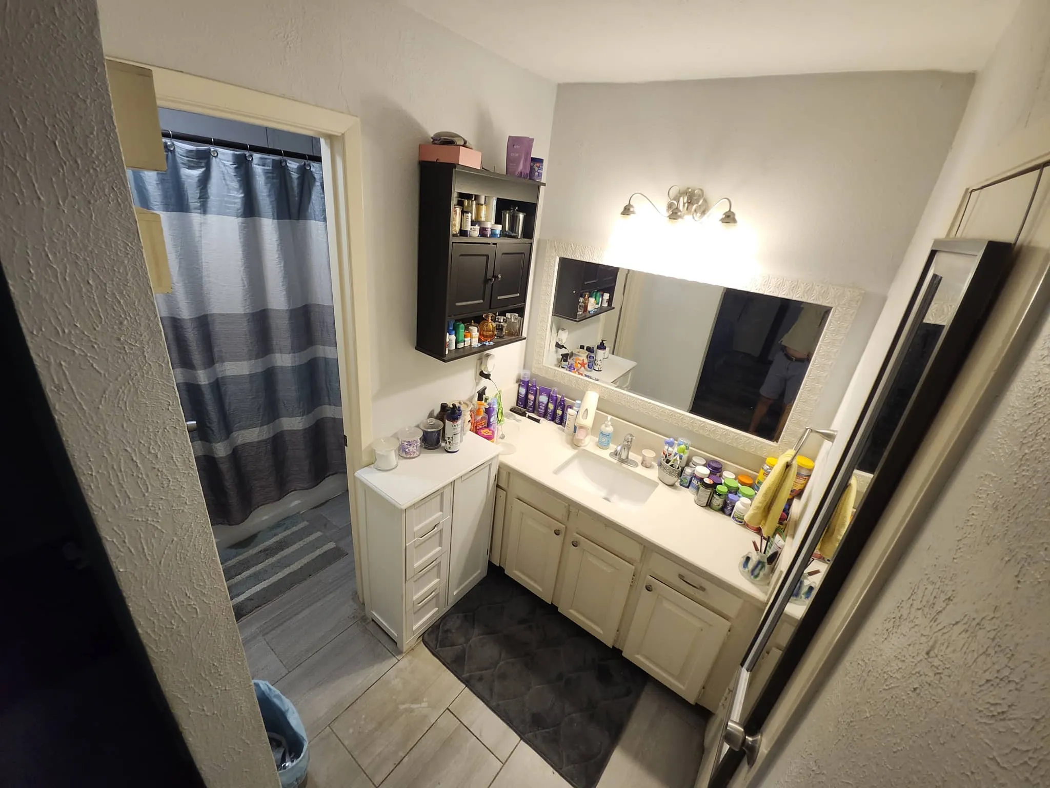 White vanity with a single basin sink and ample counter space, complemented by a large framed mirror