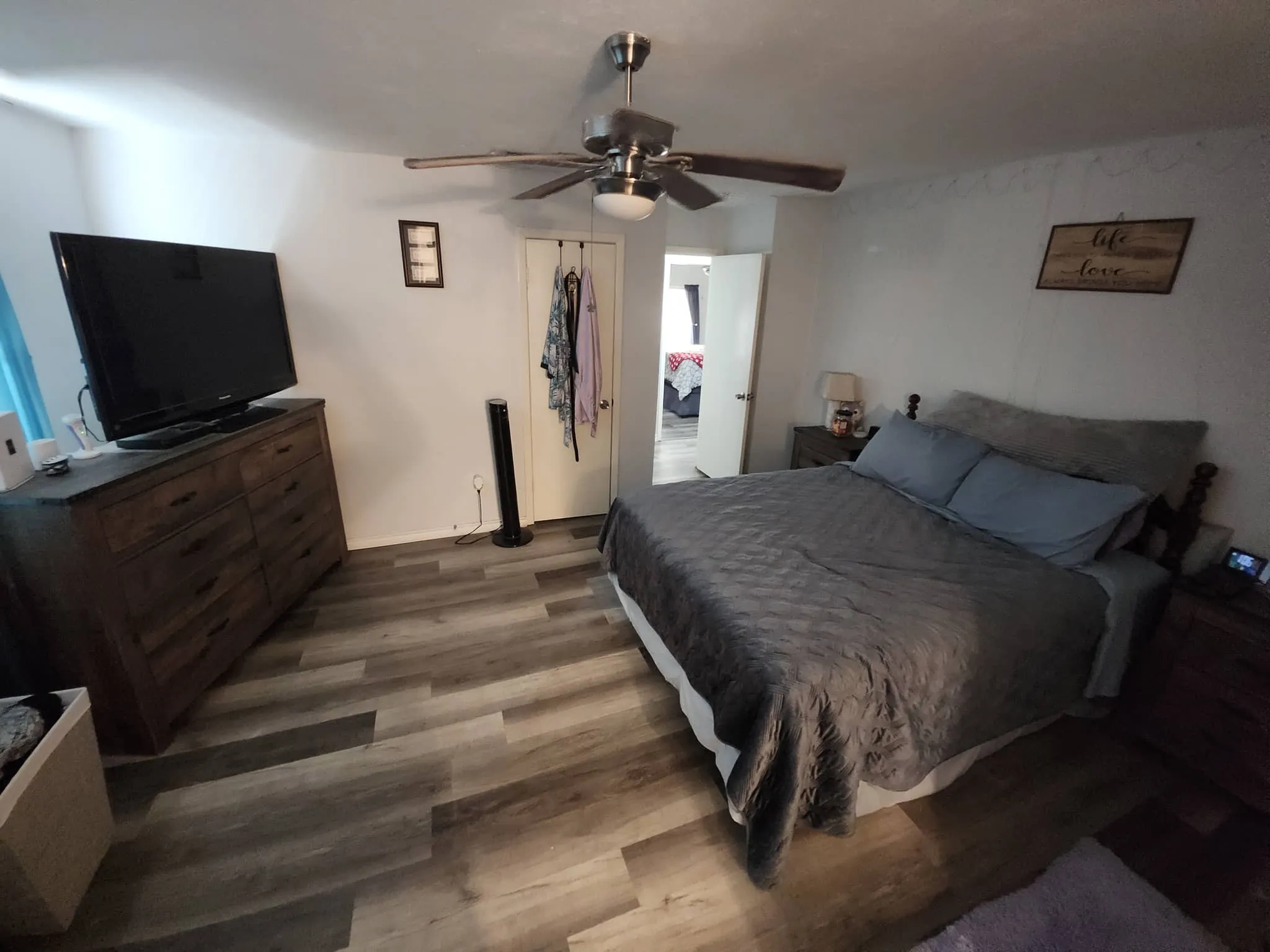 Wood-finish flooring throughout, ceiling fan with integrated lighting, and white painted walls