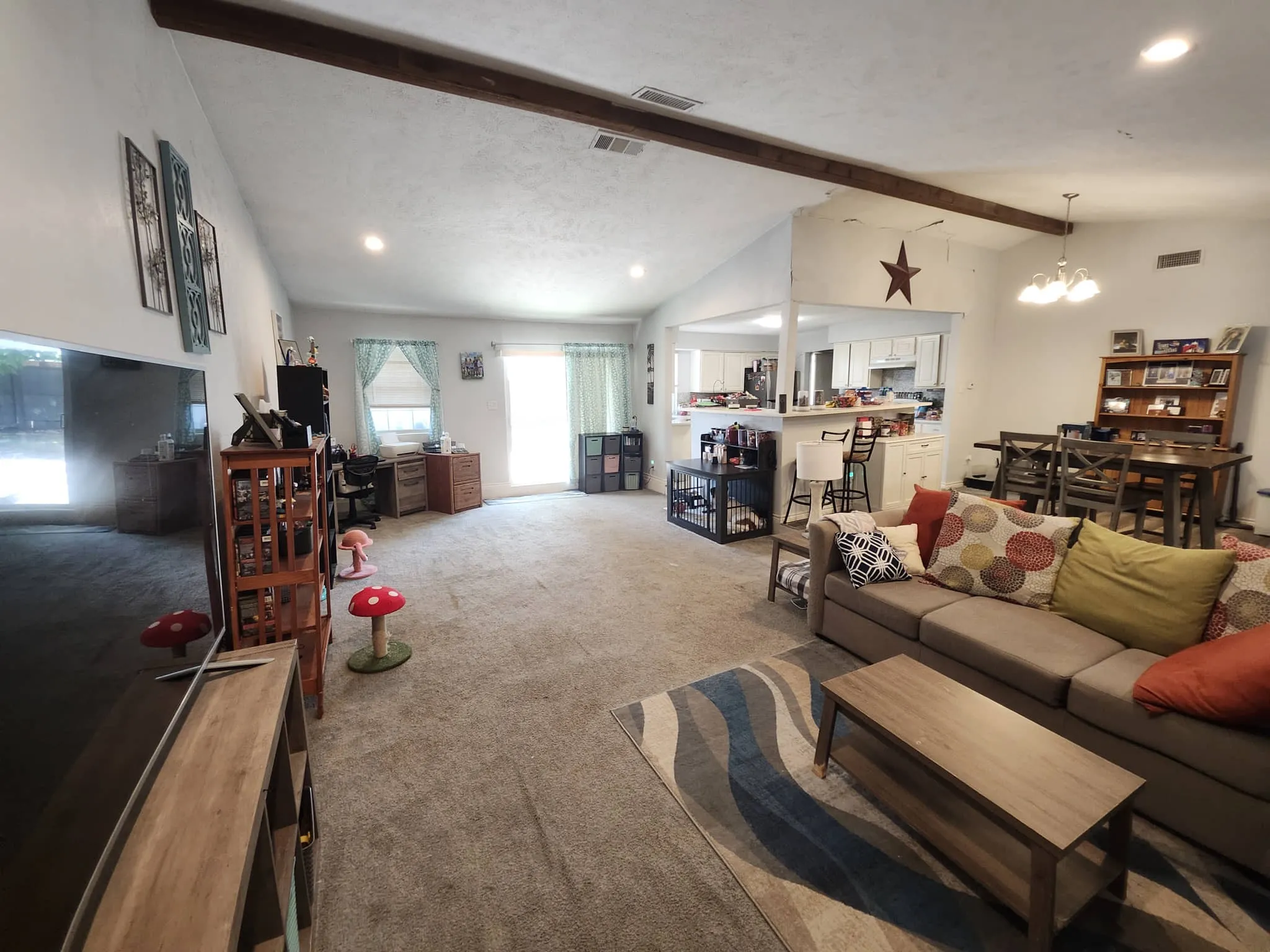 Vaulted ceilings with exposed beams, recessed lighting, and a kitchen pass-through with breakfast bar