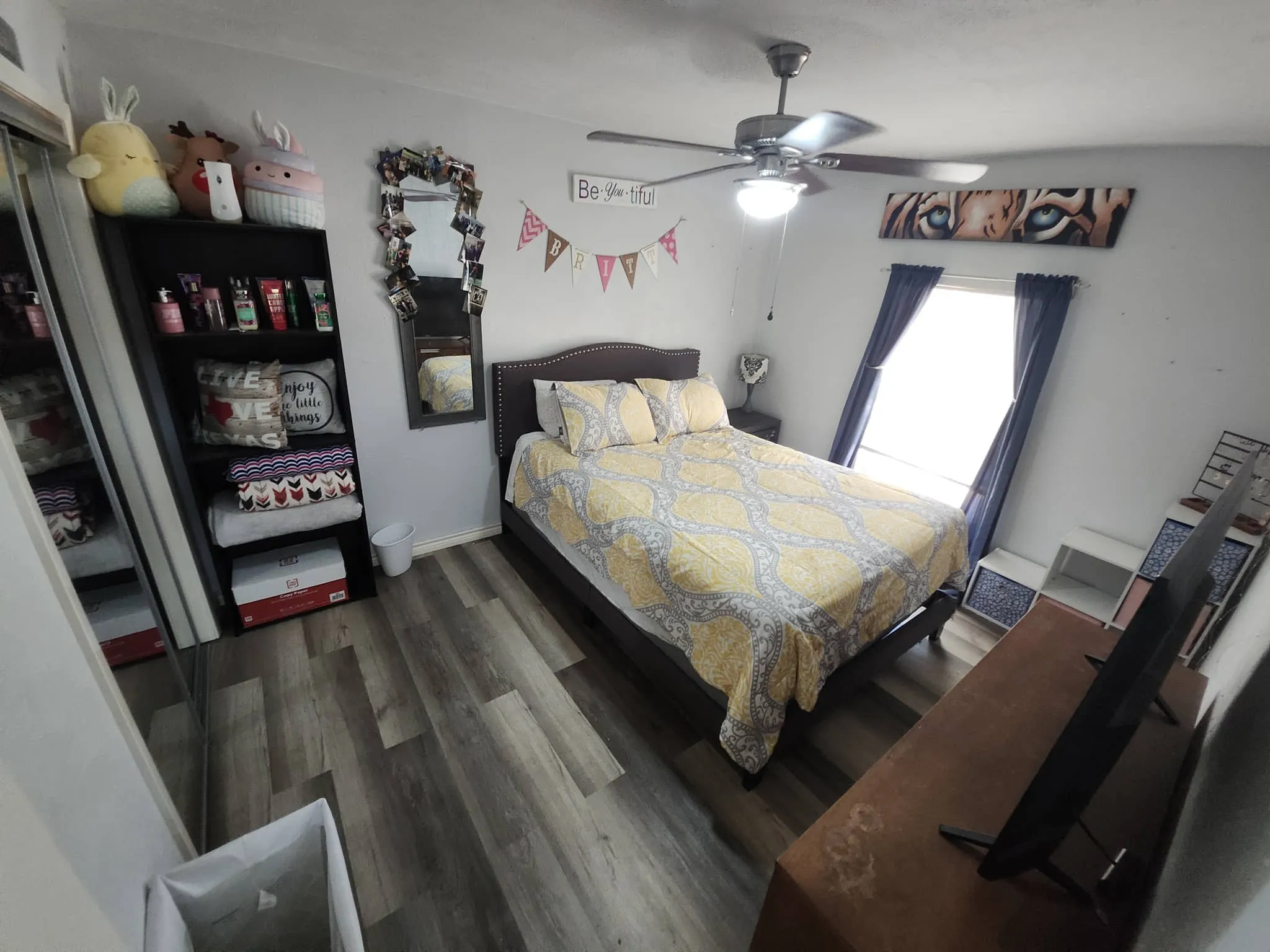 Wood-finish flooring throughout, featuring a ceiling fan with integrated lighting, and a window with natural light