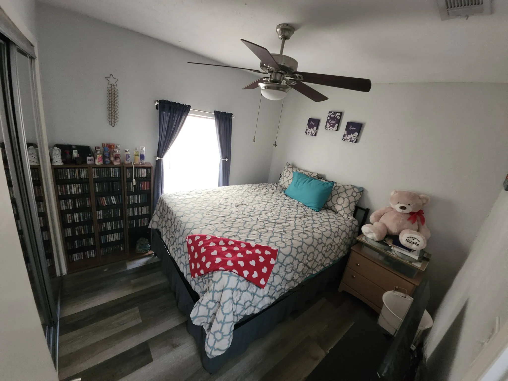 Vaulted ceiling with a ceiling fan, window with curtains, wood-finish flooring, and built-in shelving
