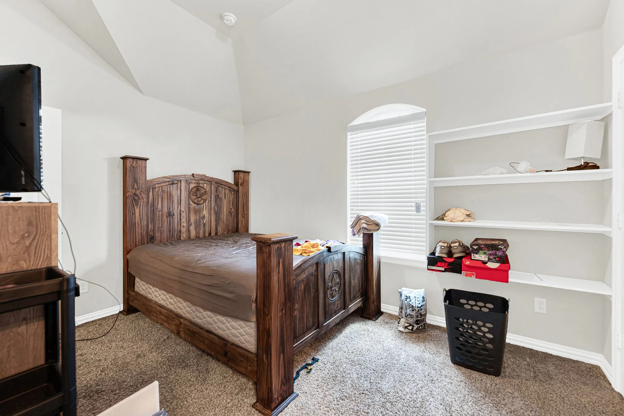 Built-in shelving recessed into the wall provides smart storage while preserving open floor space under the angled ceiling. Imagine setting up a cozy guest sanctuary where visitors can unpack and feel right at home.