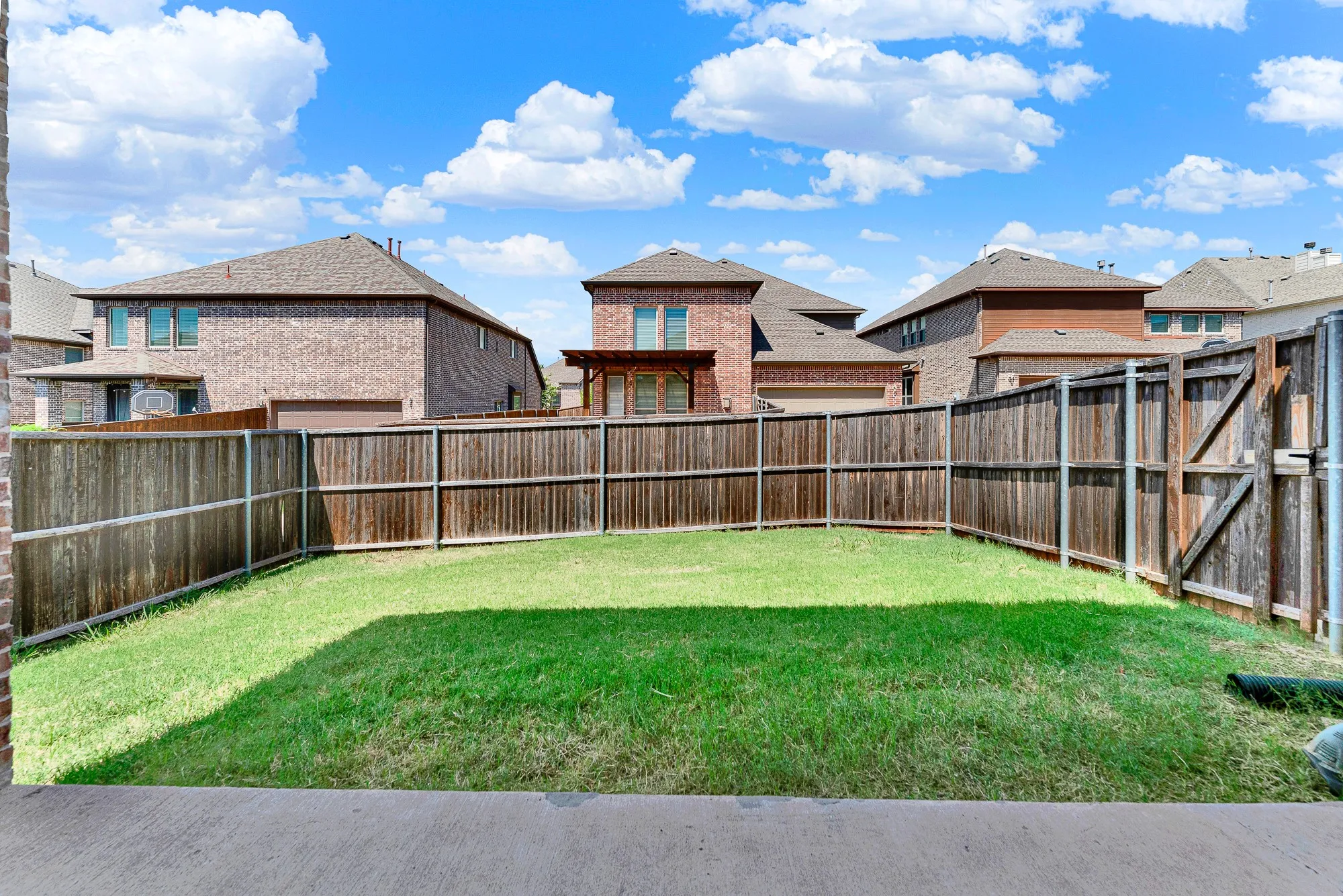 A fully enclosed, privacy-fenced lawn offers a secure green space with clear views of the open Texas sky. It is the ultimate spot for pets to run free or to set up a private outdoor play area