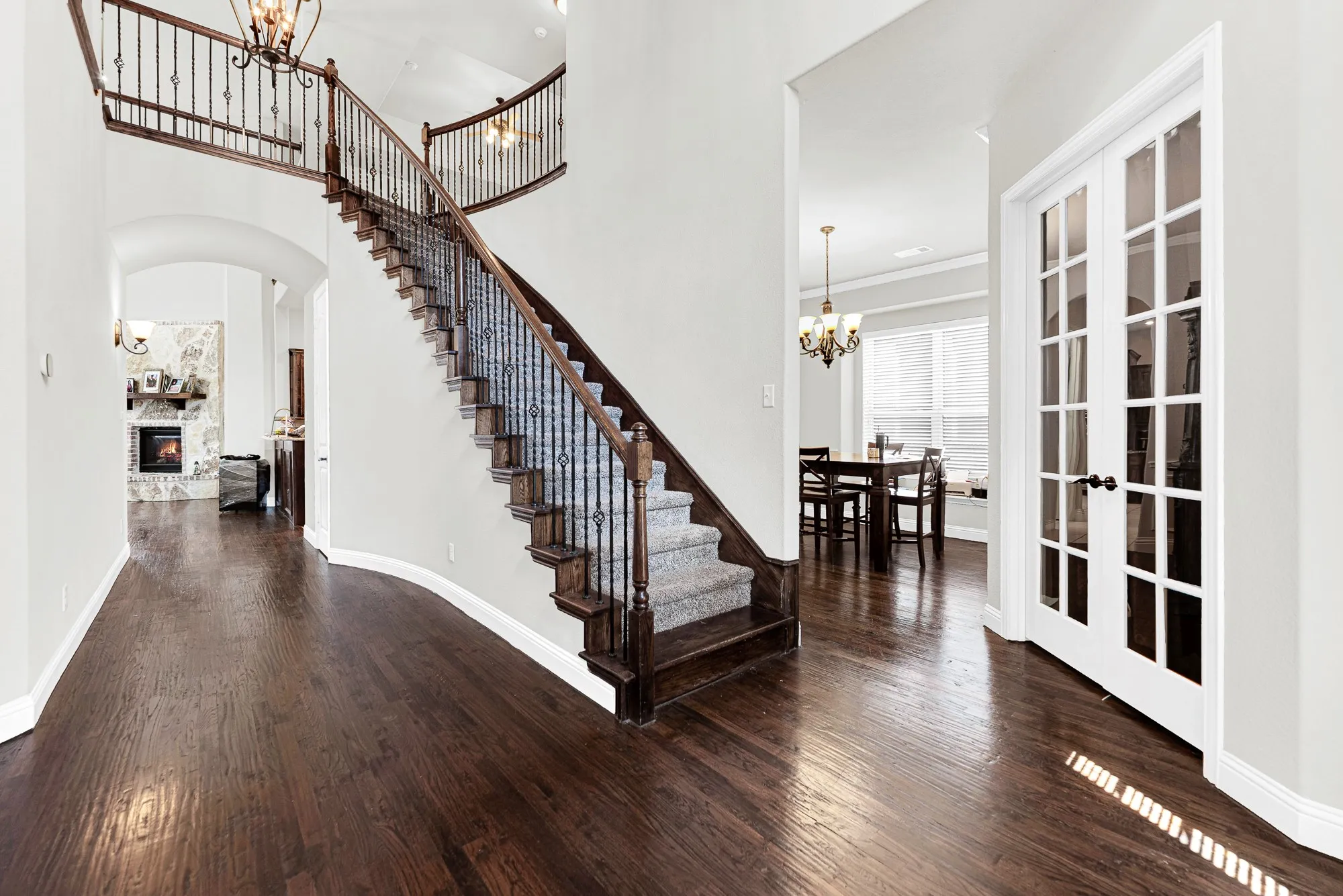 The sweeping curved staircase with wrought-iron spindles elegant sweeps upward, anchoring the entry hallway. It sets a warm, inviting backdrop for greeting guests as they arrive for holiday dinner parties.