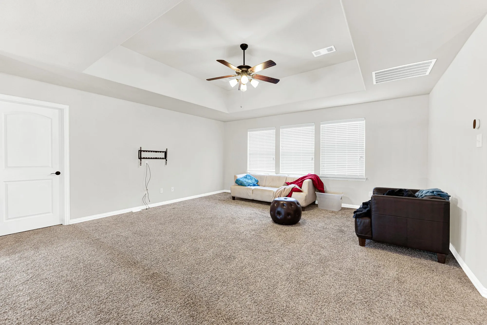 A recessed tray ceiling with a central fan anchors this expansive game room layout. Picture afternoon video game marathons or casual hangout sessions with plenty of room to stretch out.