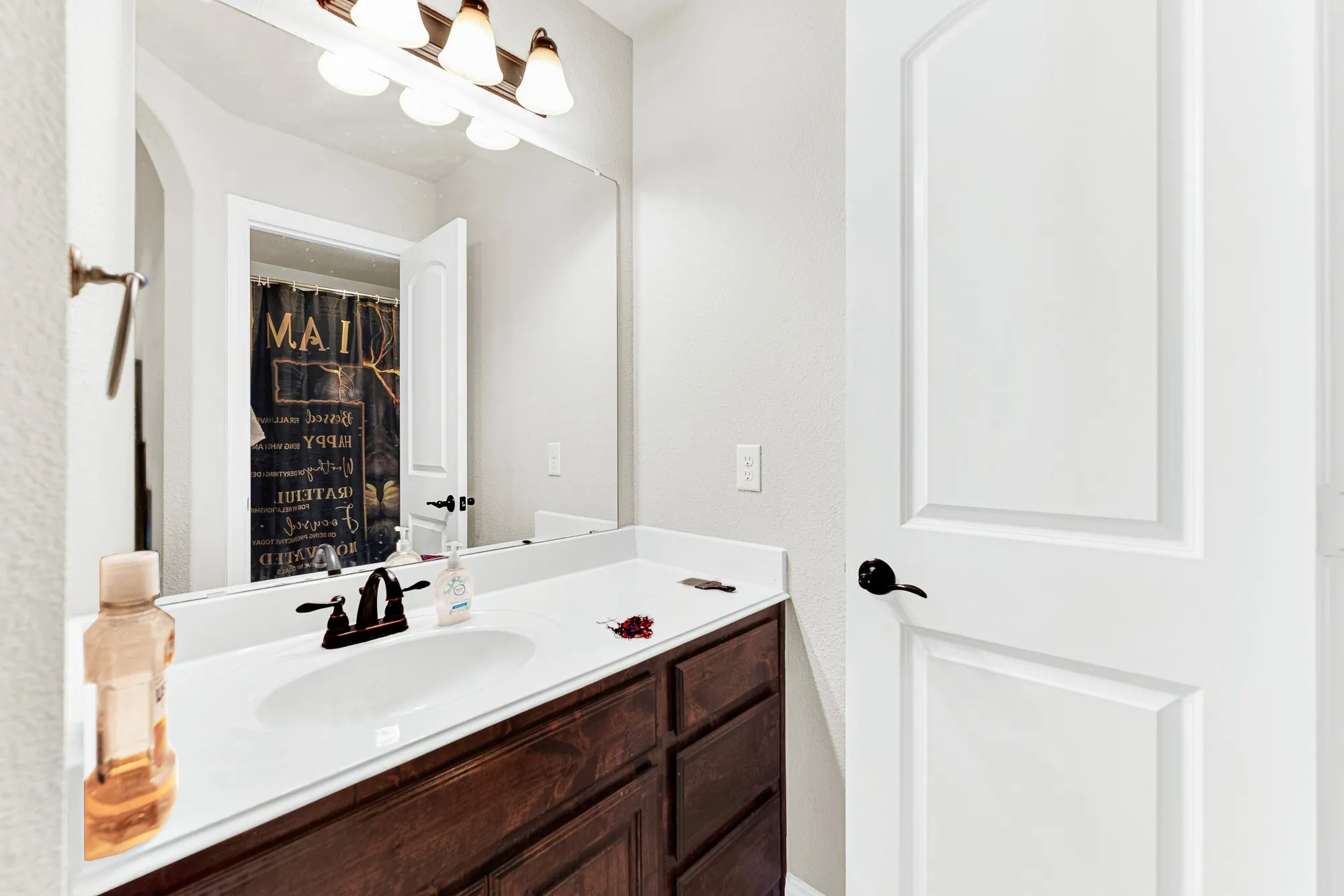 A wide mirror stretches over rich wood cabinetry to reflect light across the vanity area. It provides a comfortable, hassle-free spot for kids or guests to get ready in the morning.