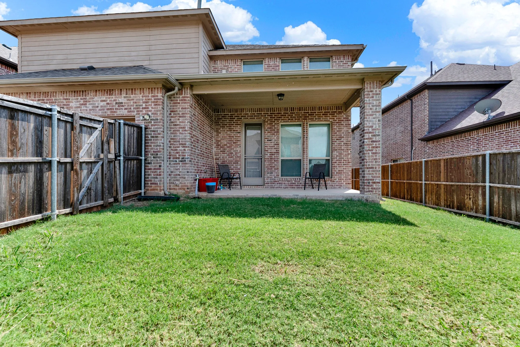 Tall brick pillars frame this sheltered outdoor seating area overlooking the entire backyard. It is an ideal setting for grilling evening meals or unwinding under the stars after work.