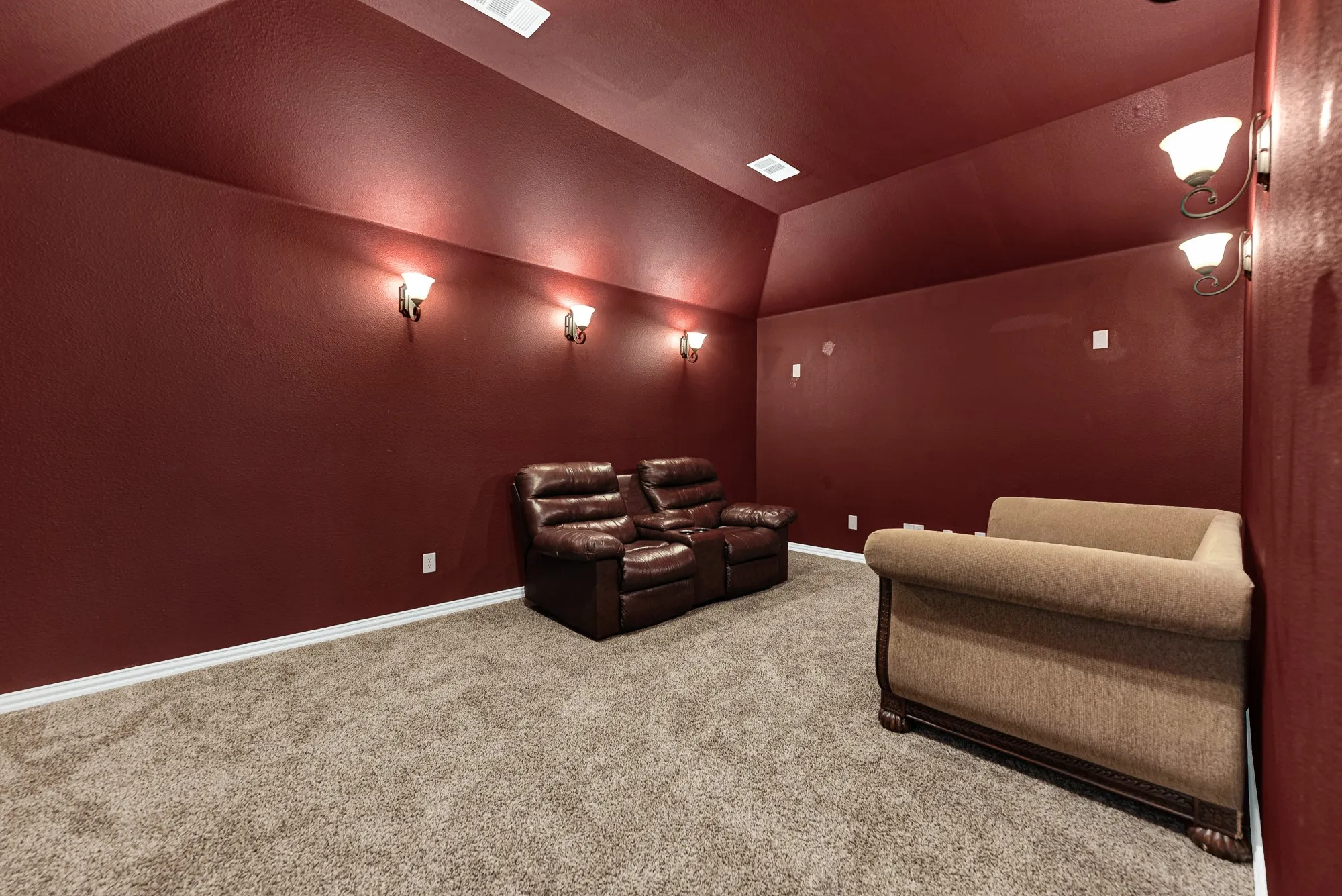 Rich crimson walls paired with ambient wall sconces create a true cinematic, cocoon-like atmosphere. Dim the lights and settle in for an authentic, immersive home theater experience on Friday night