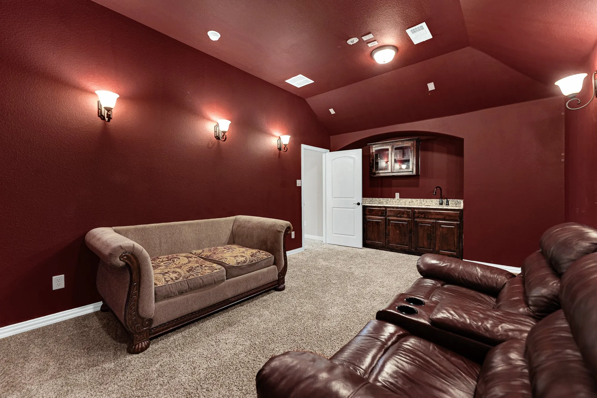 A dedicated wet bar alcove featuring dark wood cabinetry and granite counter space fits neatly into the theater room layout. Grab fresh popcorn and chilled beverages without missing a single frame of the feature film