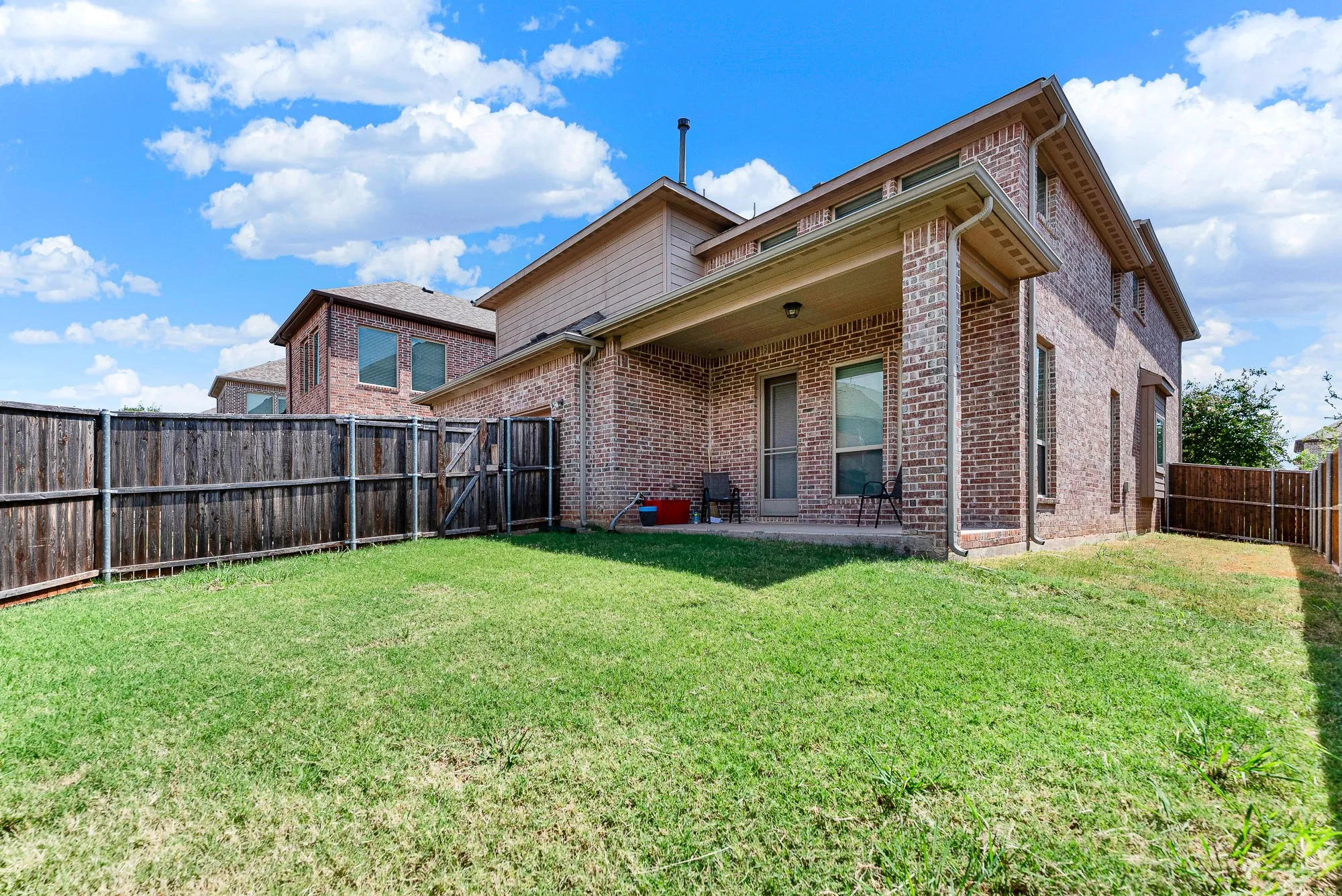 Expansive green turf spans the backyard, offering plenty of elbow room along the side elevation. Picture hosting lively weekend lawn games with friends and family with space to spare.