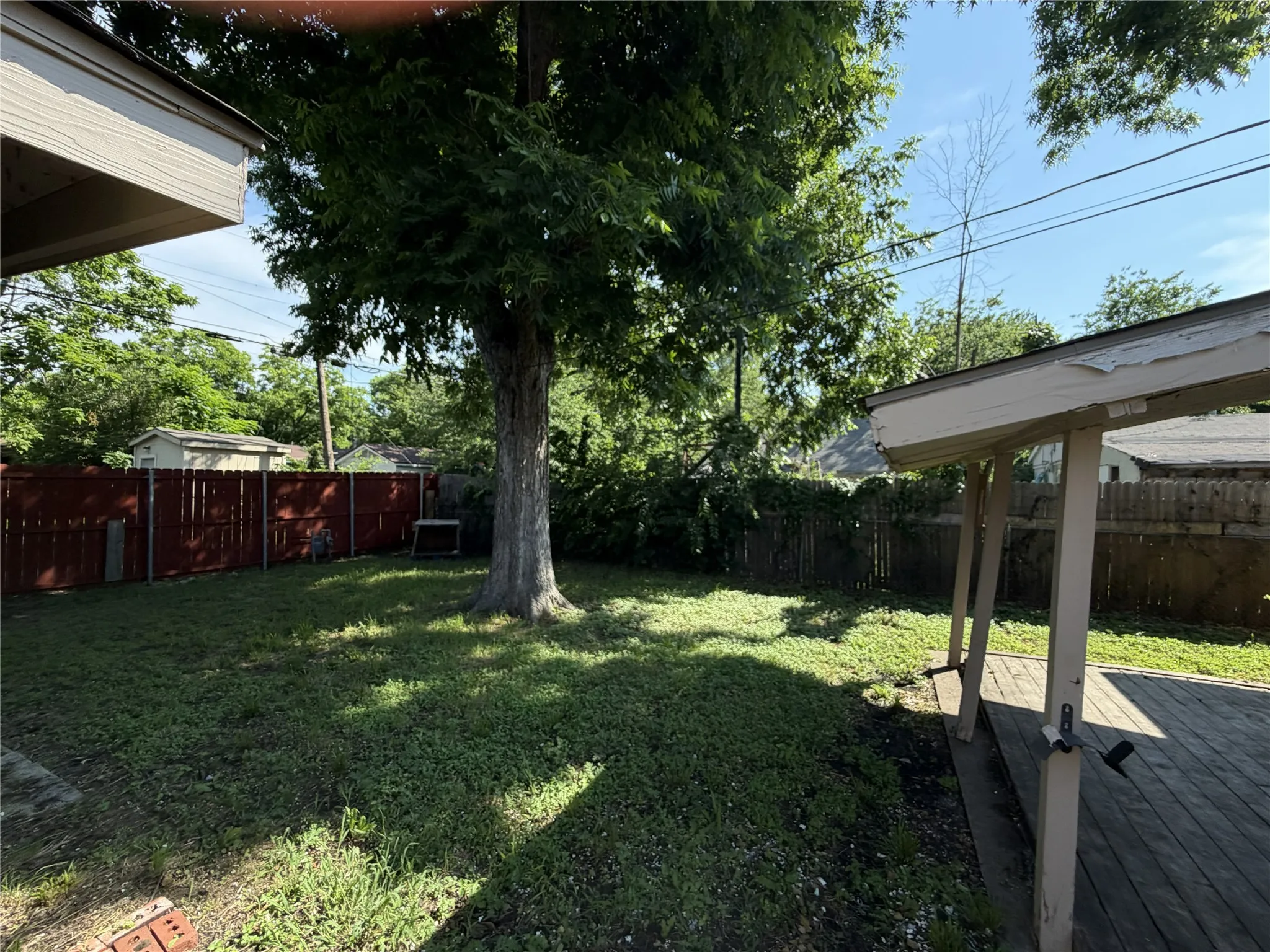 Expansive backyard featuring a mature tree, wood fencing, and a wooden deck