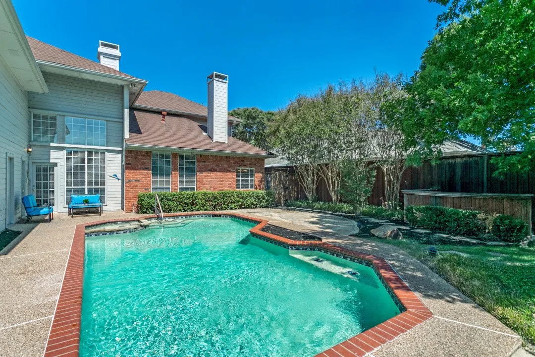 In-ground pool with integrated spa and red brick coping