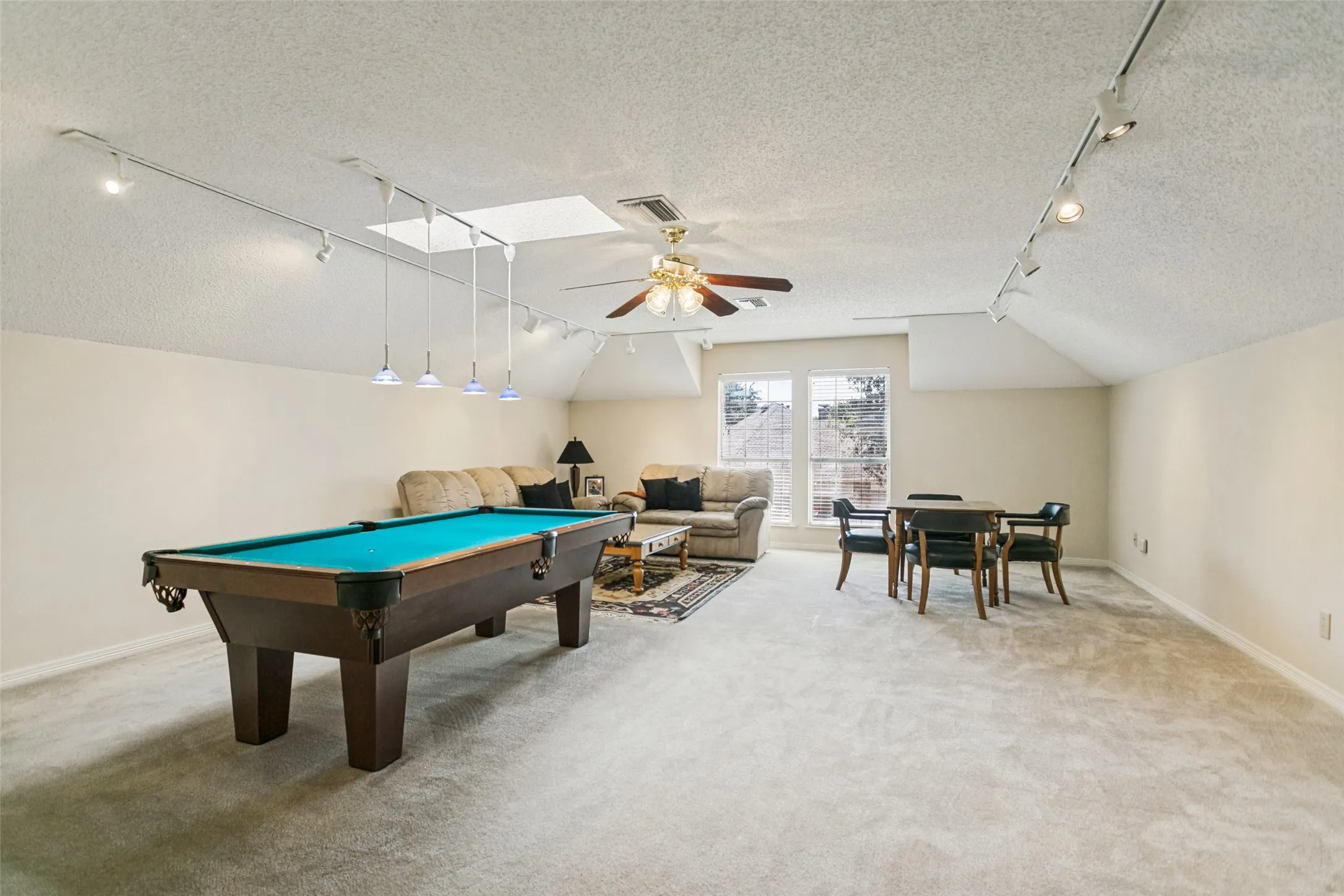 Spacious room featuring carpet flooring, track lighting, and a ceiling fan