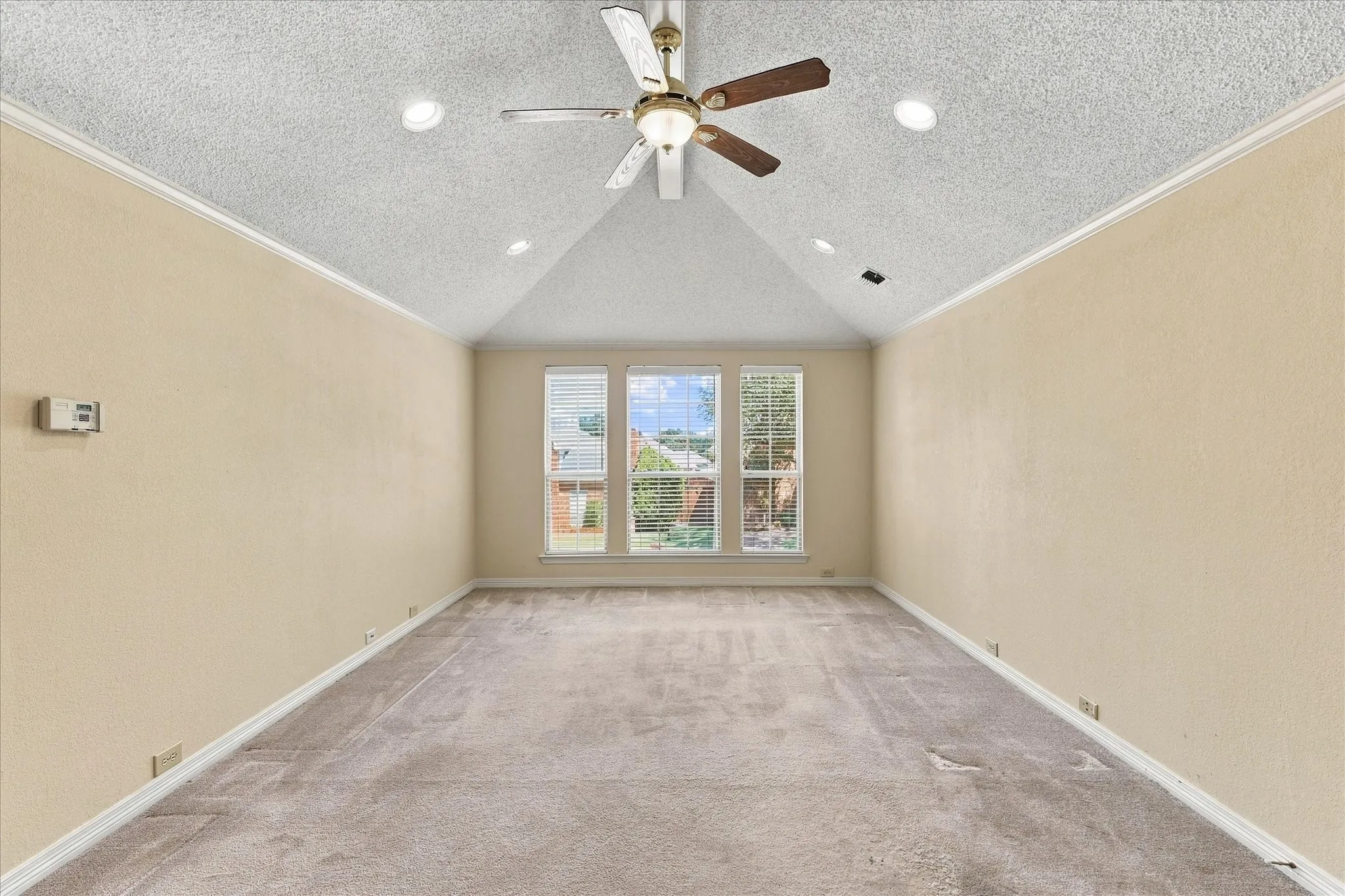 Vaulted ceiling with a ceiling fan and recessed lighting, three windows with blinds, and neutral carpeting