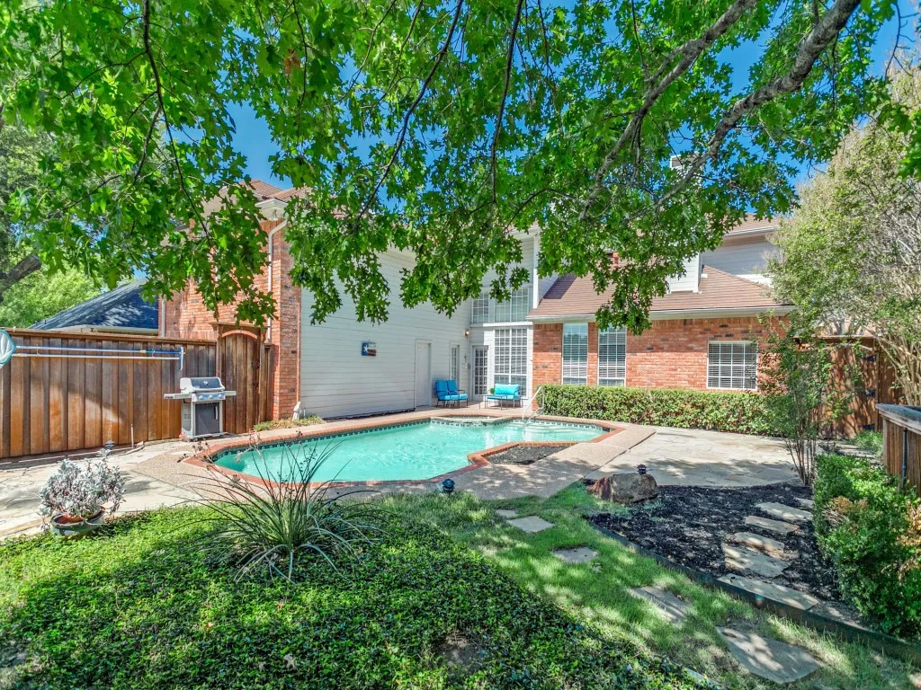 Backyard with a built-in swimming pool, flagstone patio, and mature trees