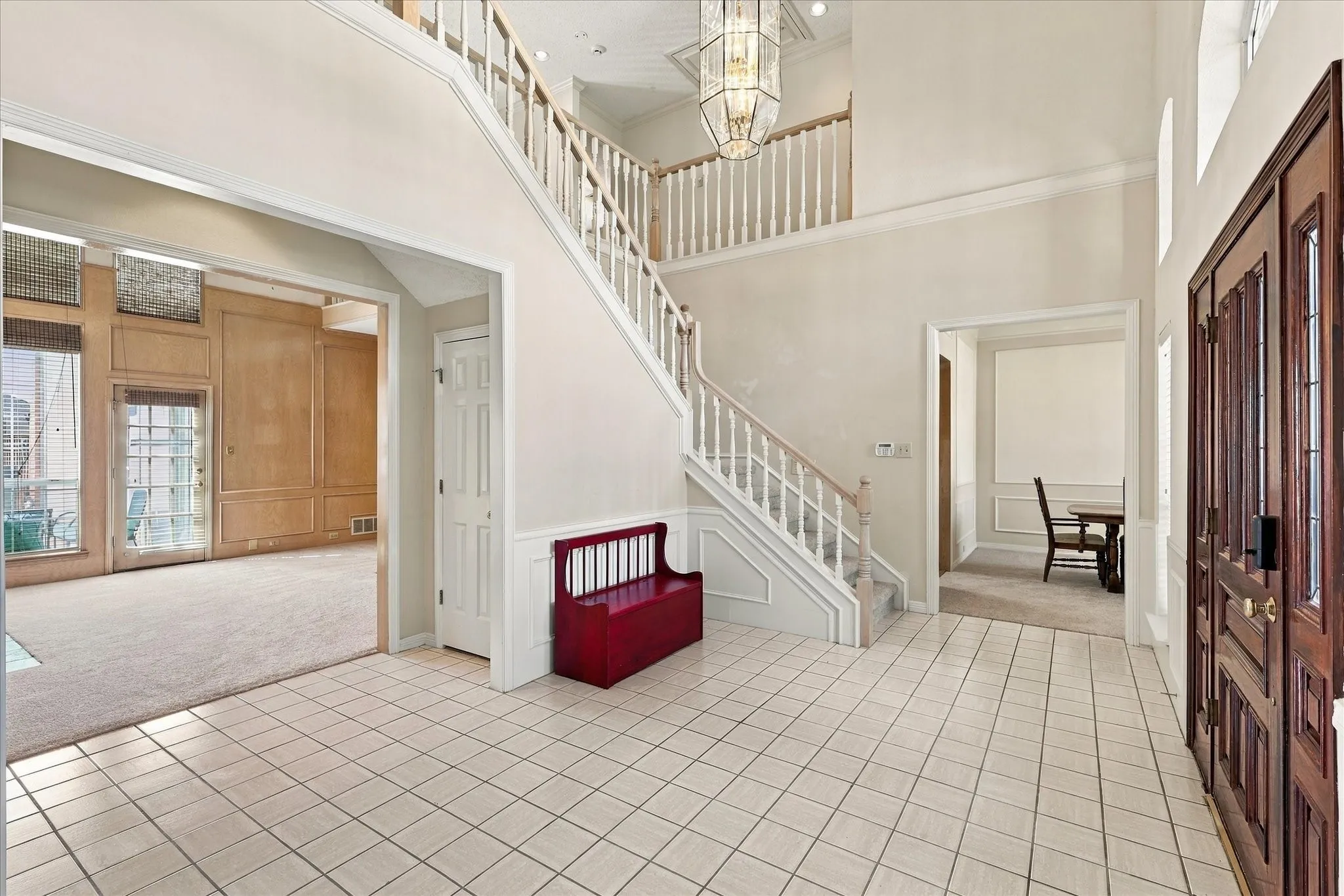 Tiled entry foyer with a grand staircase and overhead chandelier