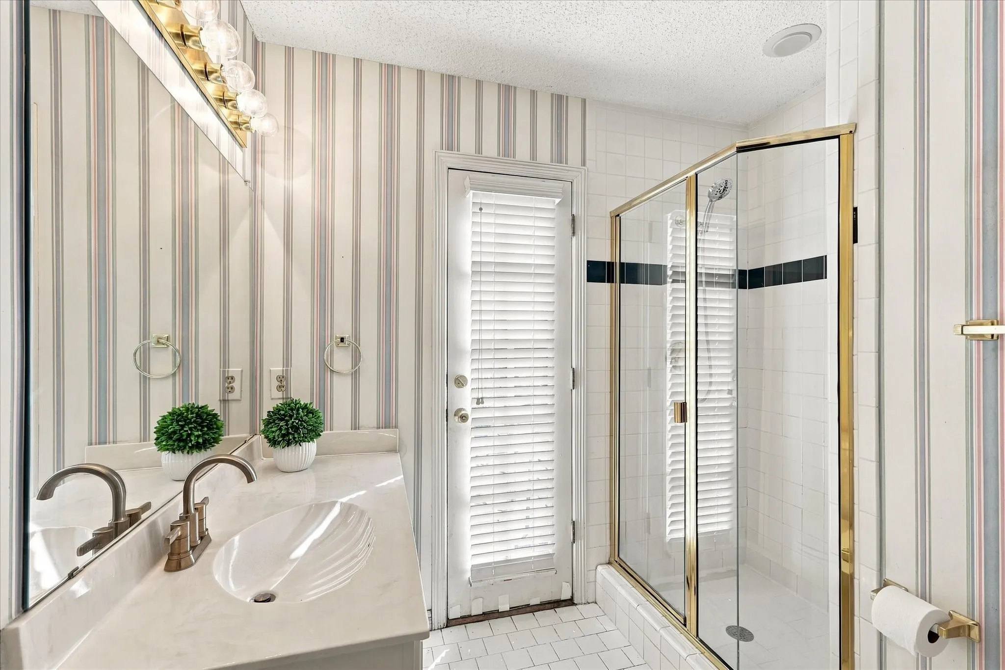 Vanity with integrated sink, brass-finish fixtures, and wall-mounted lighting