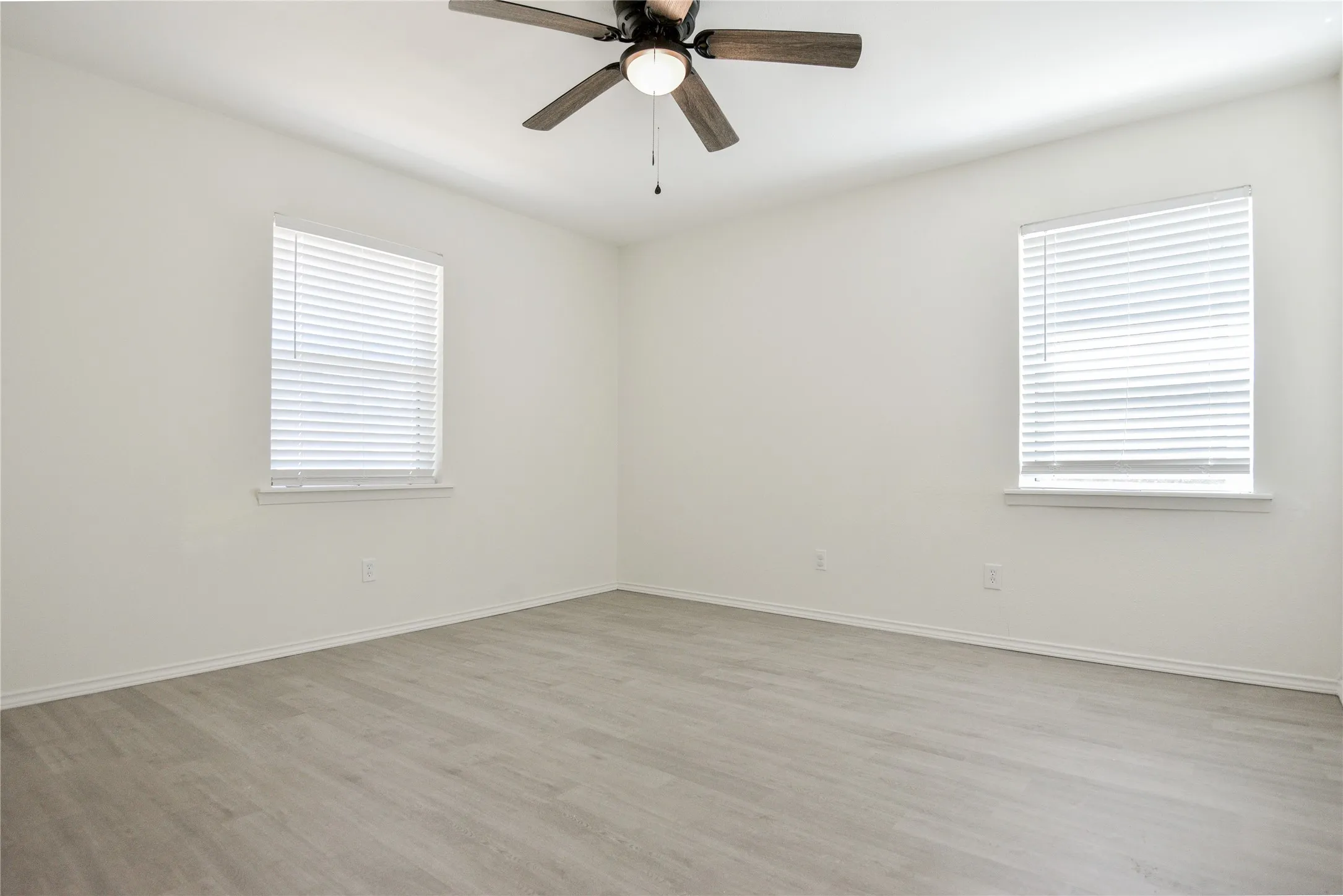 Wood-finish flooring, white walls, and a ceiling fan with integrated lighting