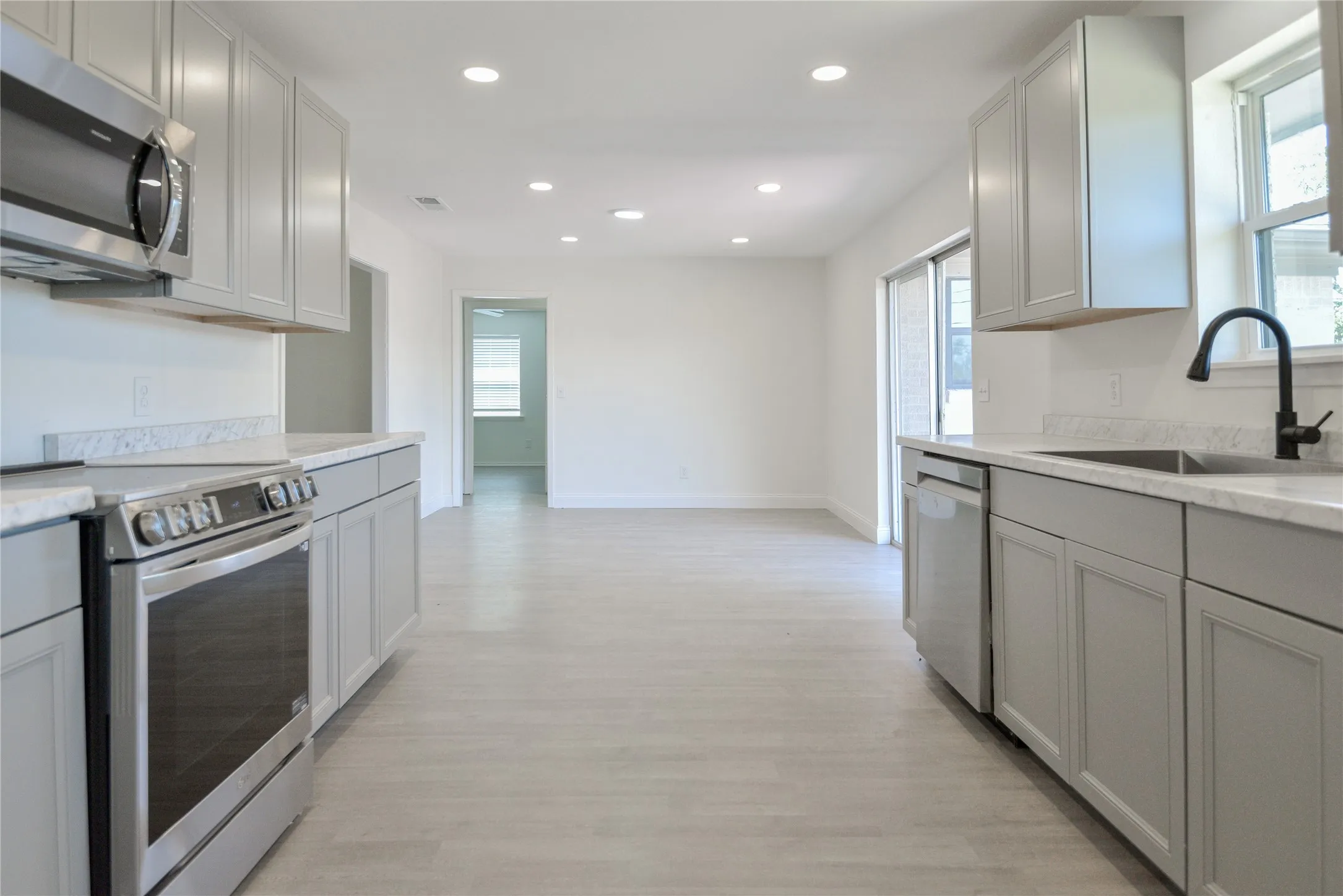 Kitchen featuring light grey cabinetry, stainless steel appliances, light-toned countertops, and recessed lighting