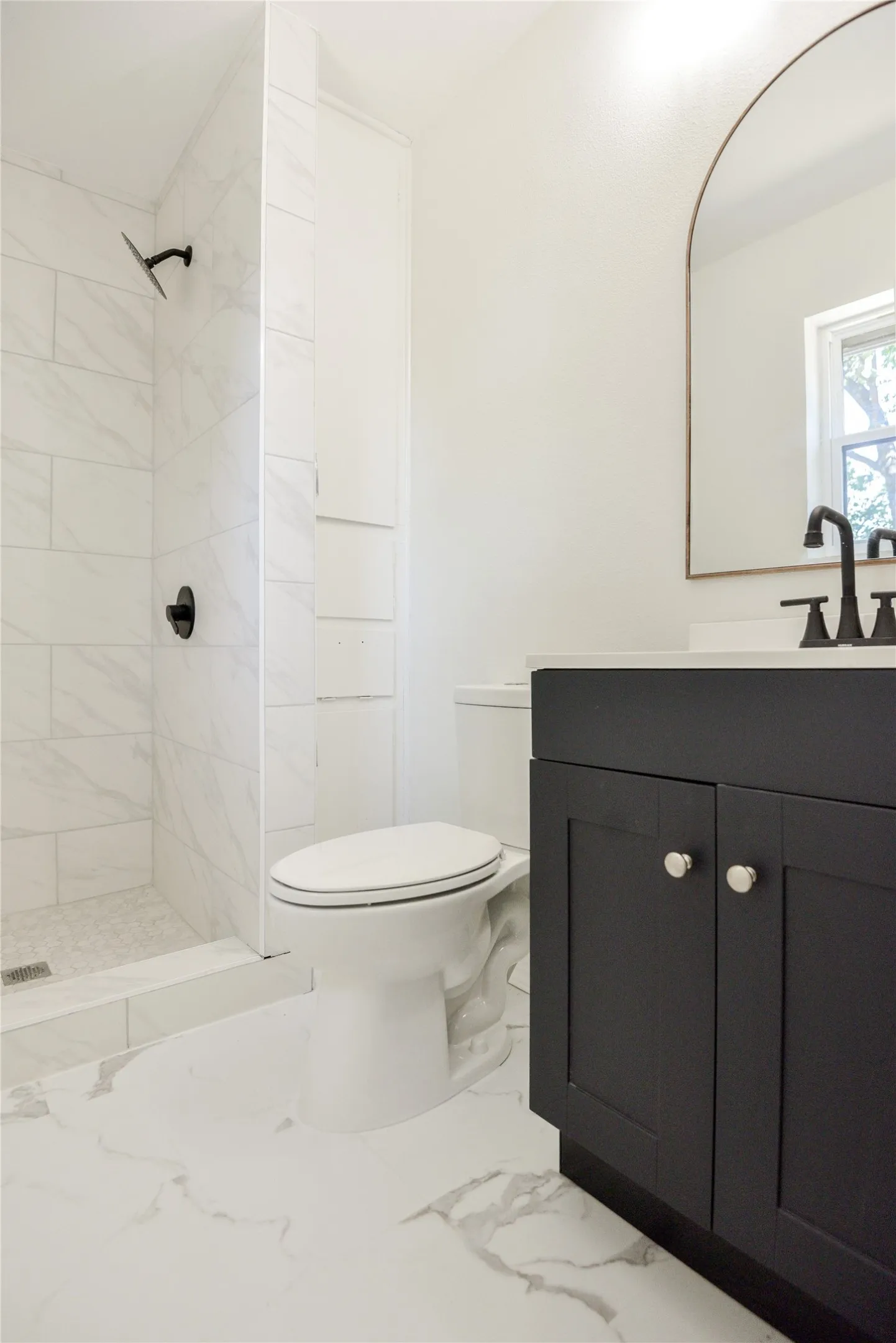 Walk-in shower with large format tile, floor-to-ceiling tile surround, and matte black fixtures