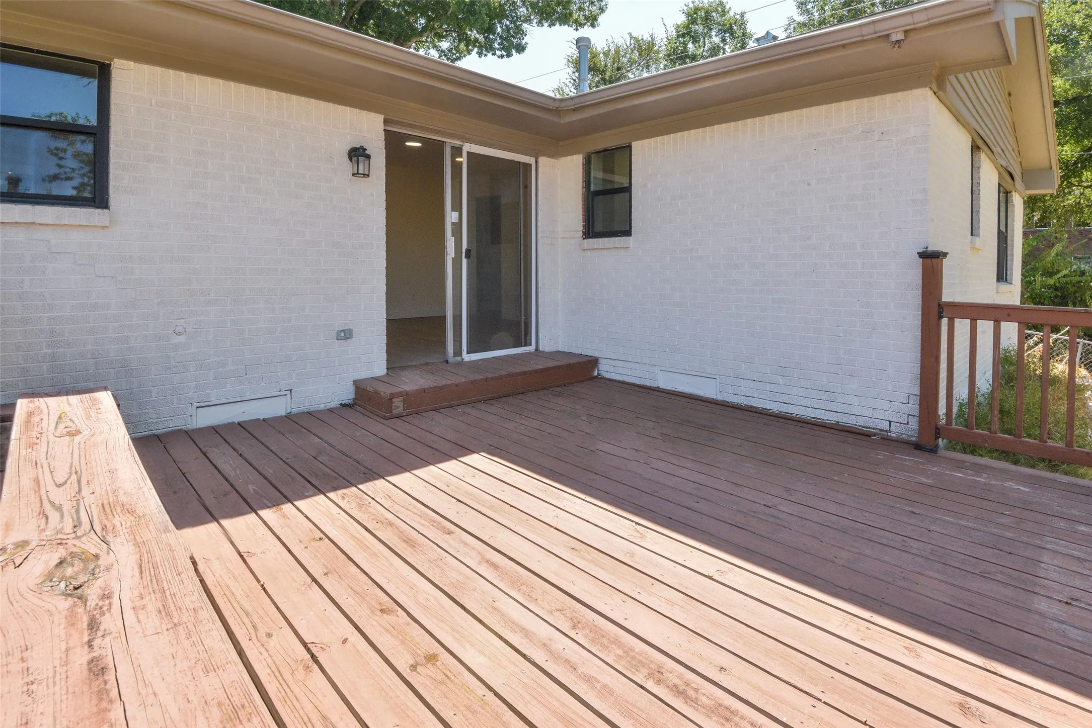 Expansive wood deck with a built-in bench, offering direct access to the interior through a sliding glass door