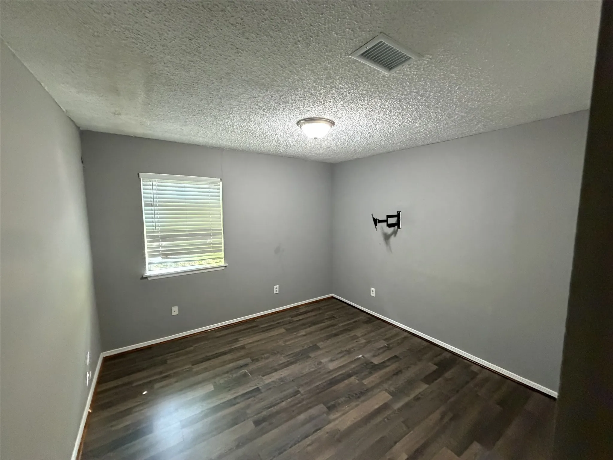Wood-finish flooring with baseboards, a window with blinds, and a flush mount ceiling light fixture