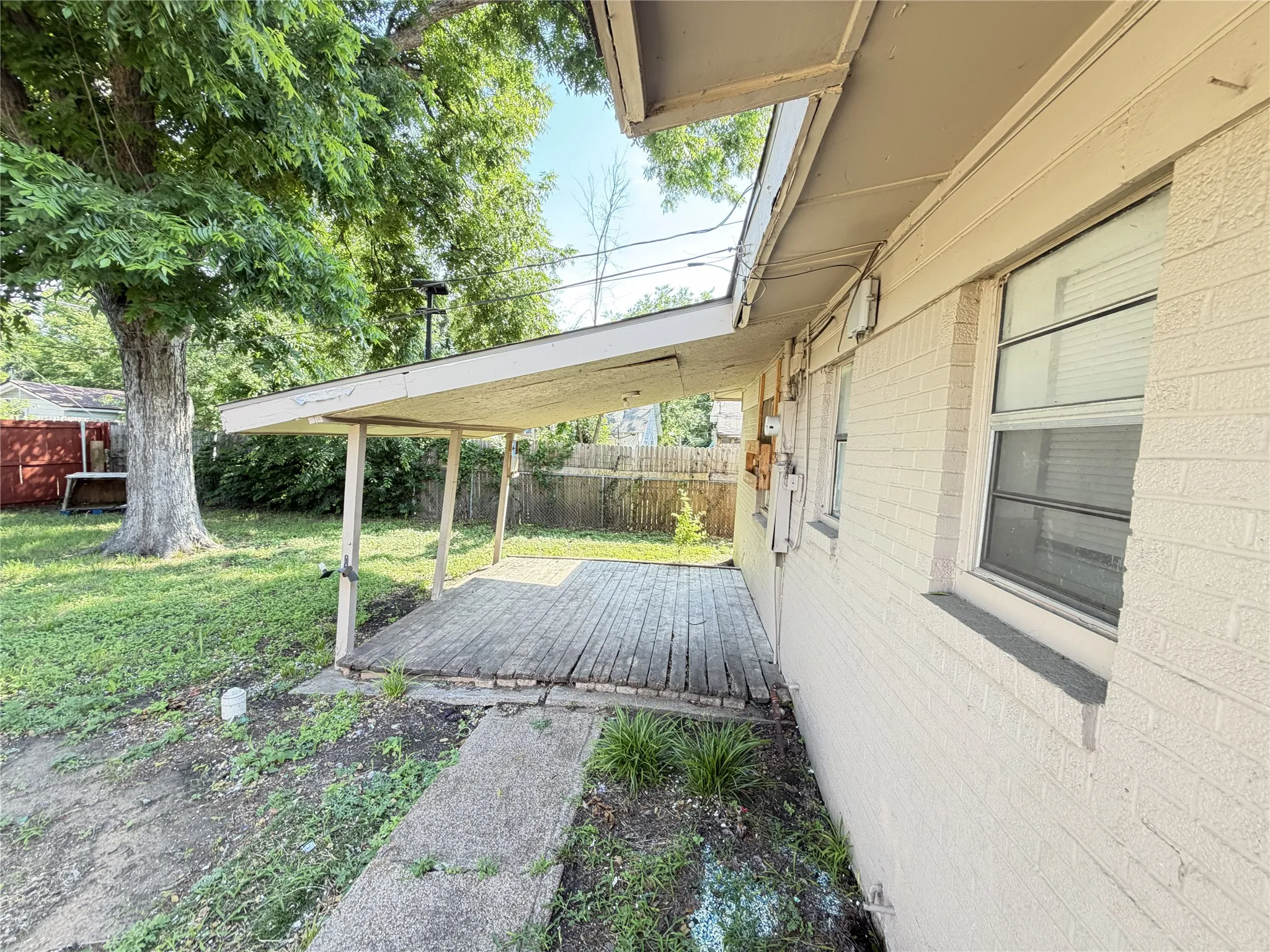 Covered porch with wood-finish decking, concrete walkway, and a brick exterior