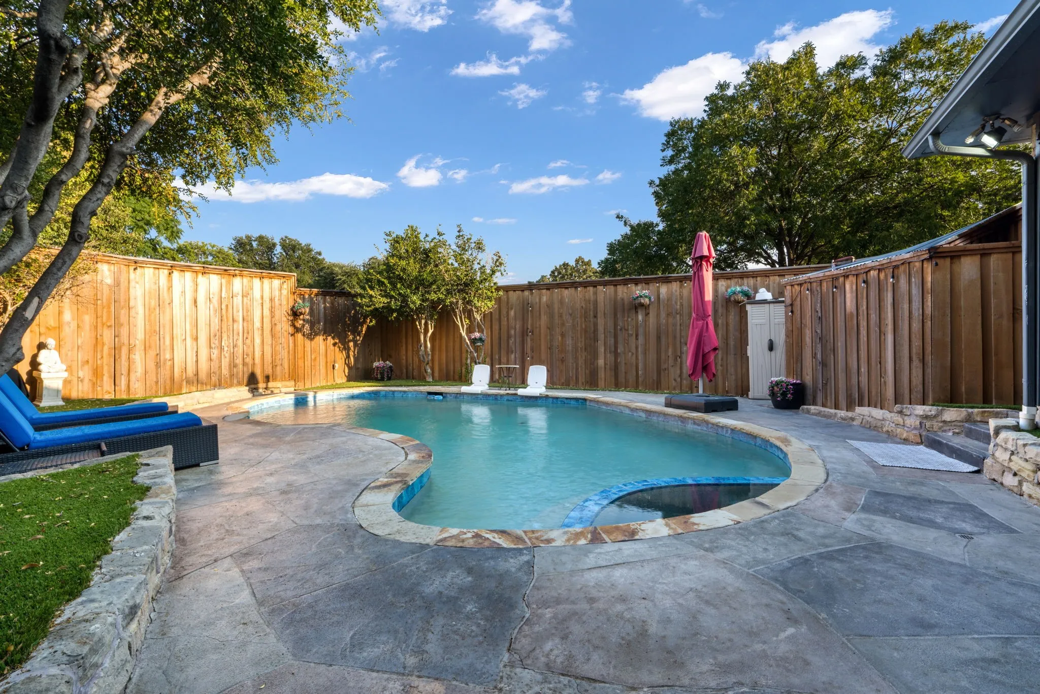 Freeform swimming pool with integrated spa and stone coping.  No maintenance turf, board on board wood fence