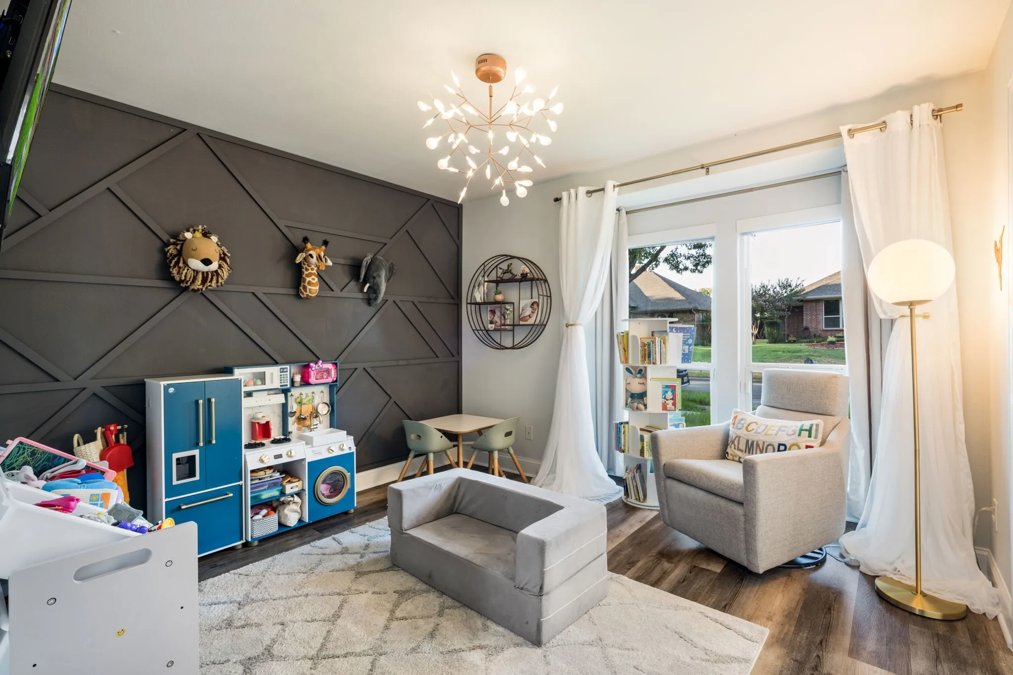 Feature wall with geometric paneling, wood-finish flooring, large window, and decorative chandelier