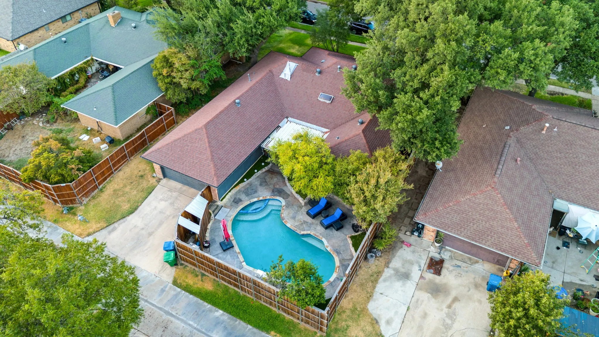 L-shaped residence featuring a private swimming pool, surrounding patio, and mature trees, attached rear facing 2 car garage with driveway